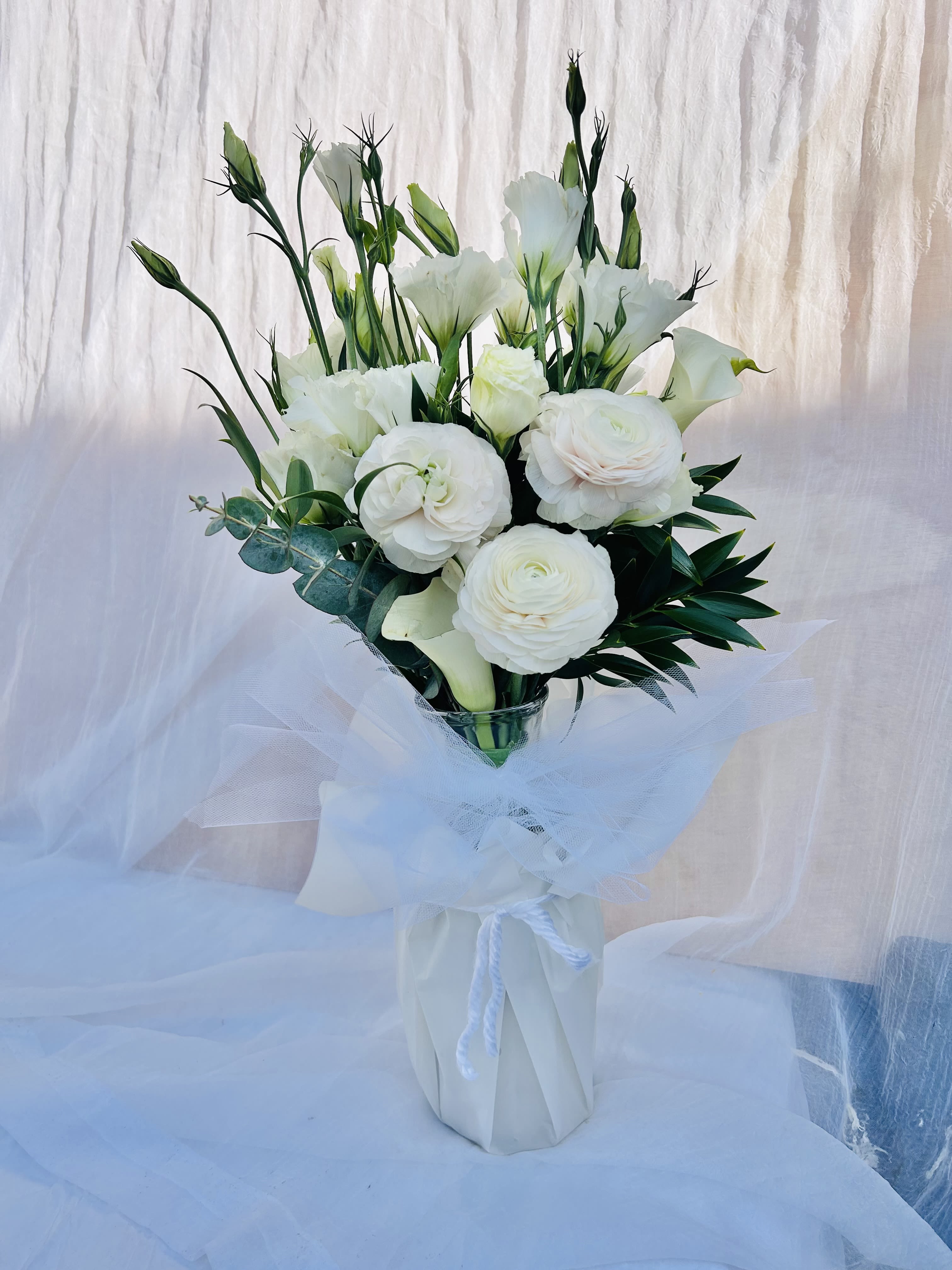 Fondly - Beautiful arrangement featuring ranunculus, calla lillies, and green accents. 