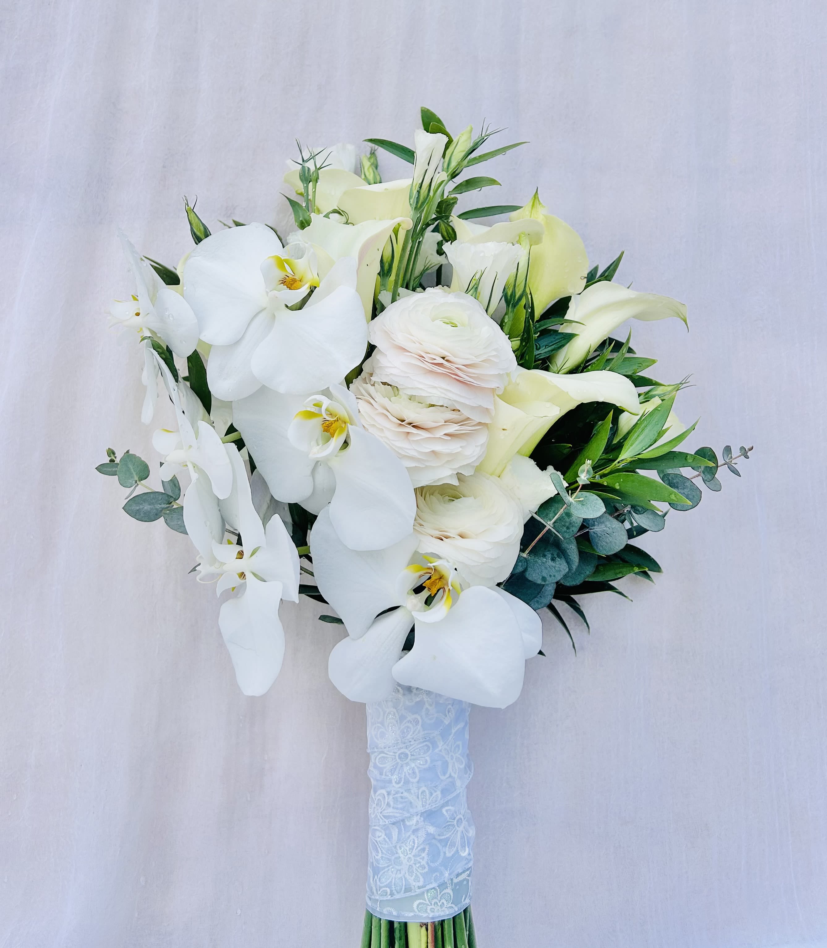 Devoted To You - Beautiful bridal bouquet featuring white orchids, calla lillies, ranunculus and green accents. 