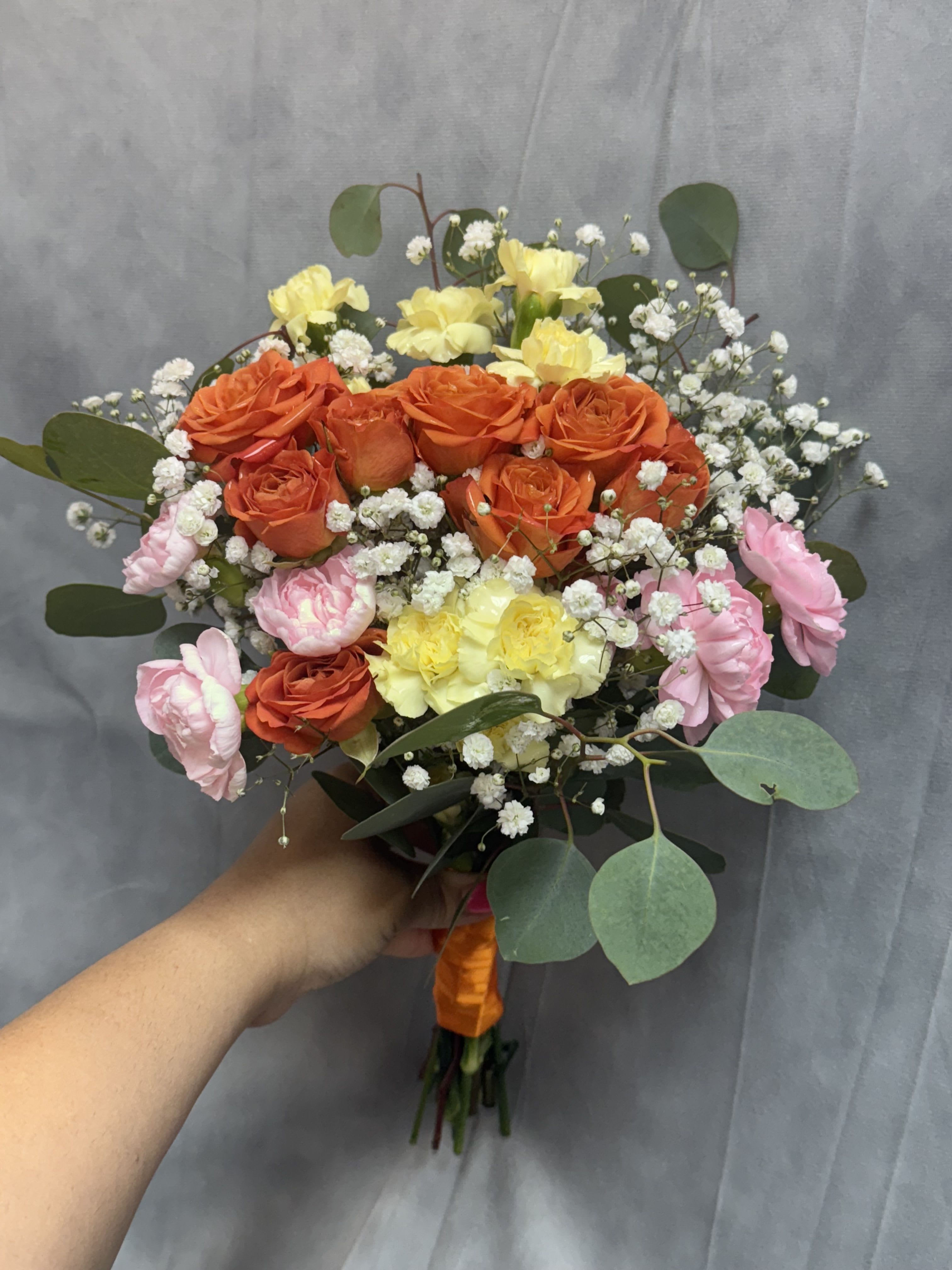 Sweet sunrise prom bouquet  - Orange spray roses with pink, yellow mini carnations and white baby's breath, wrapped with greenery ,beautifully wrapped for a cheerful,-style prom bouquet