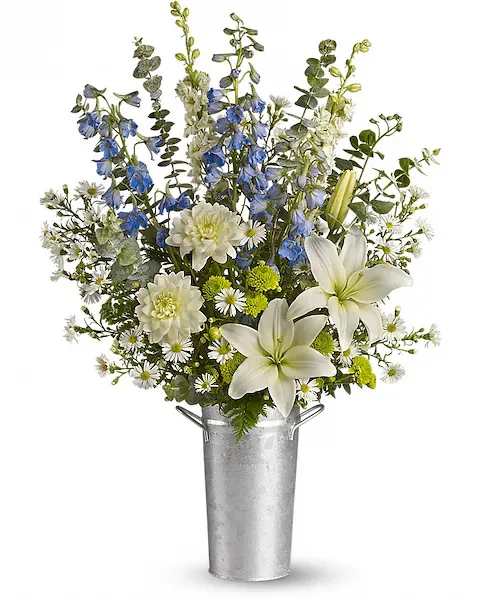 White lilies and blue flowers in a tall metal bucket