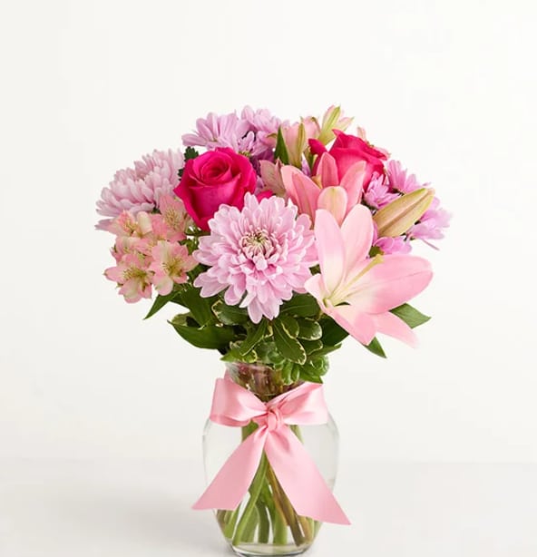 Mother's Embrace - This floral arrangement celebrates the comfort of Mom's hug with lovely pink and lavender blooms displayed in a glass vase and tied with a pink satin bow.