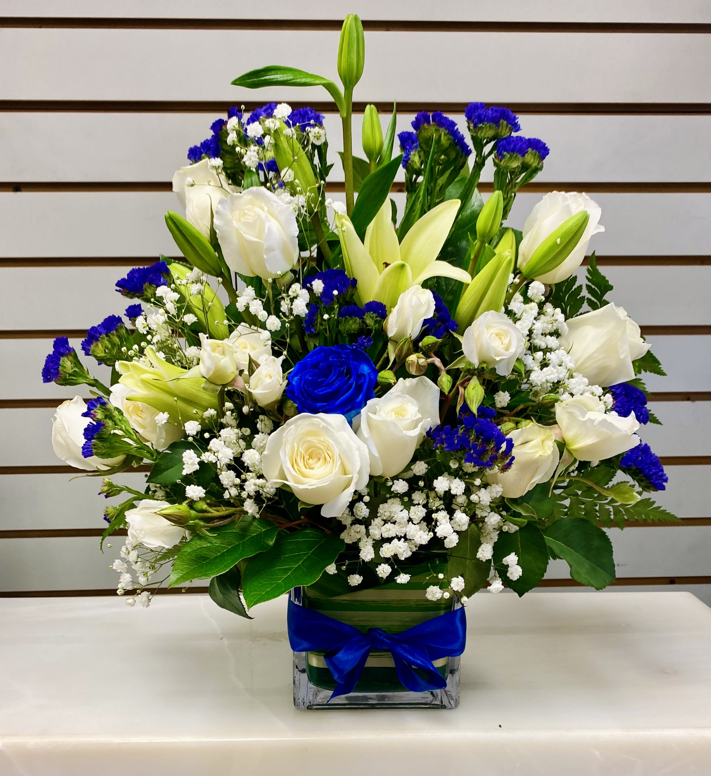 Roses and Lilies  - White Roses, lilies, spray roses, statice, mixed greenery and baby’s breath garnished with ribbon.  