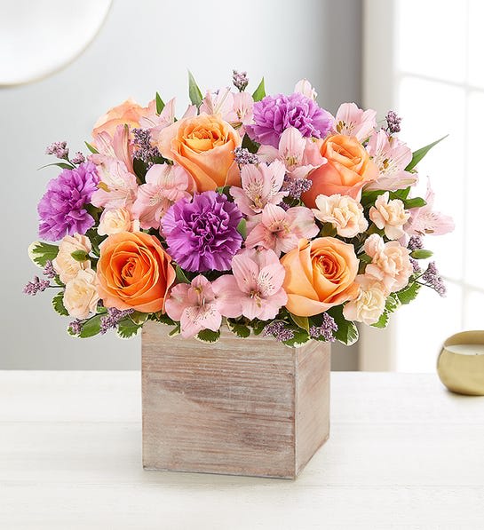 Peach roses and pink flowers arranged in a wooden box