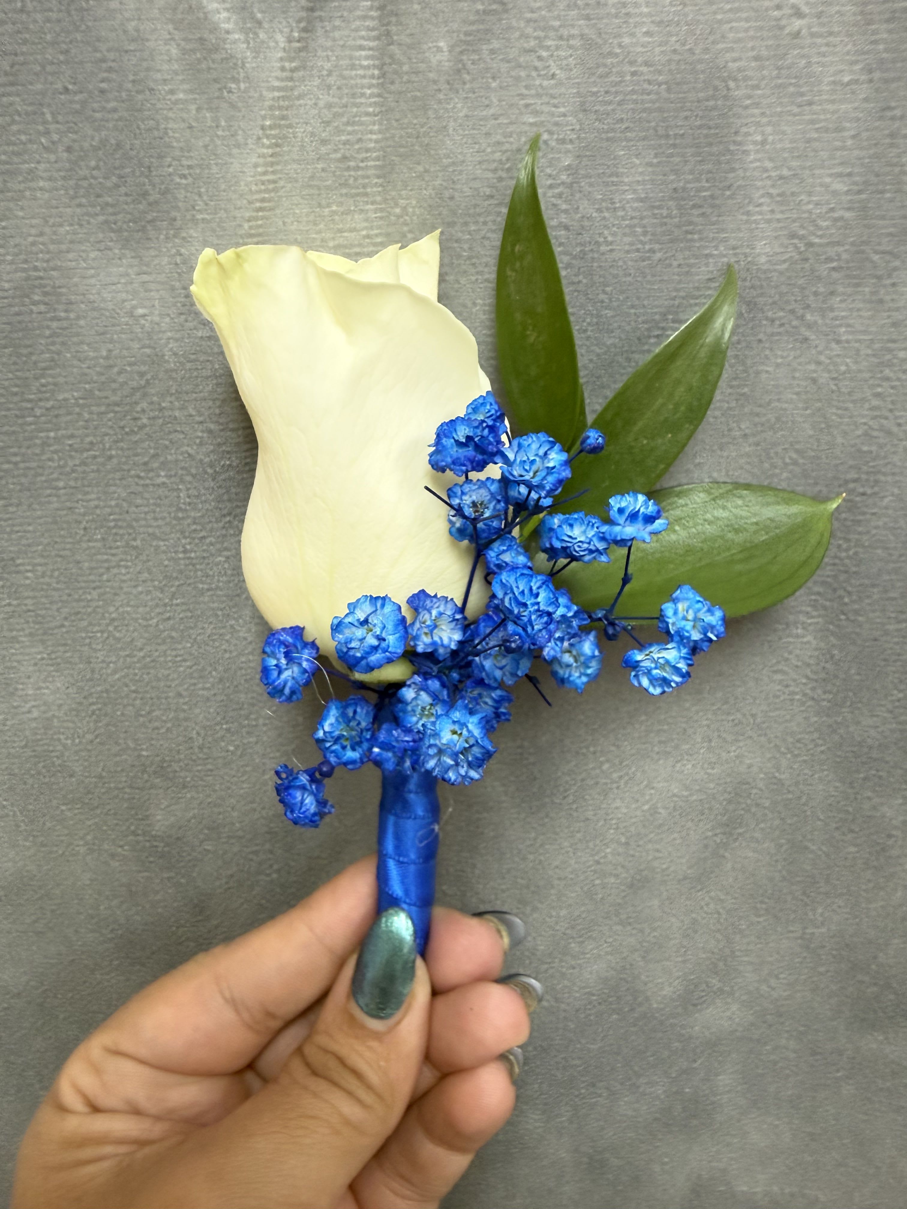 Royal blue white boutonnière  - White rose with royal blue baby's breath and green leaves, wrapped in royal blue satin ribbon