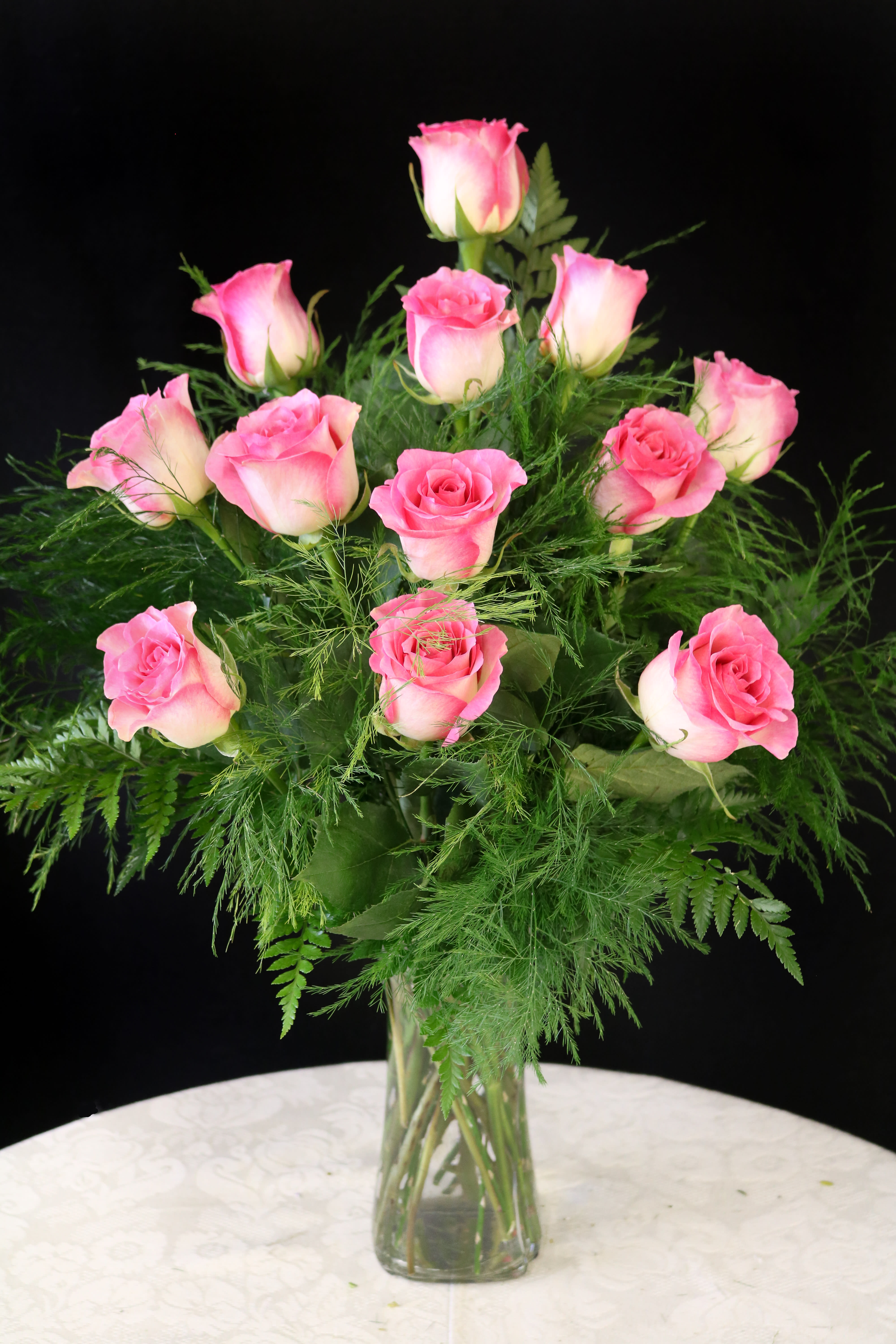 Pink roses arranged in a clear glass vase with airy greenery