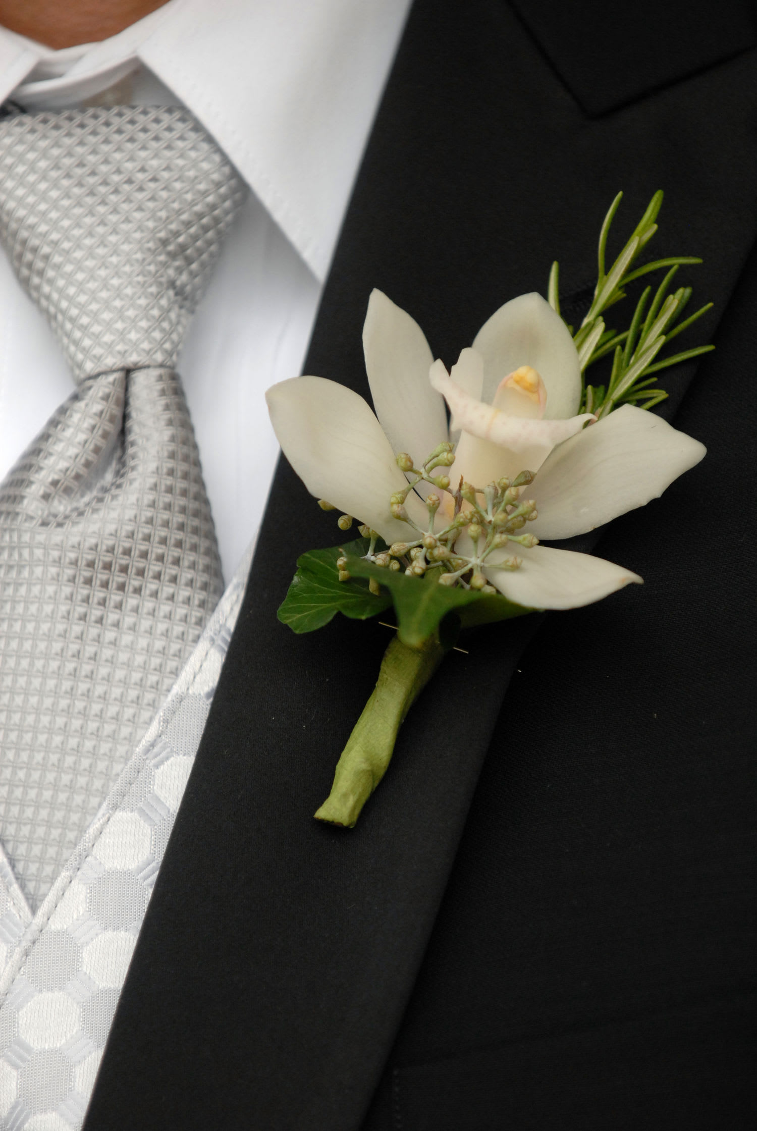 White orchid boutonniere pinned to a black suit jacket
