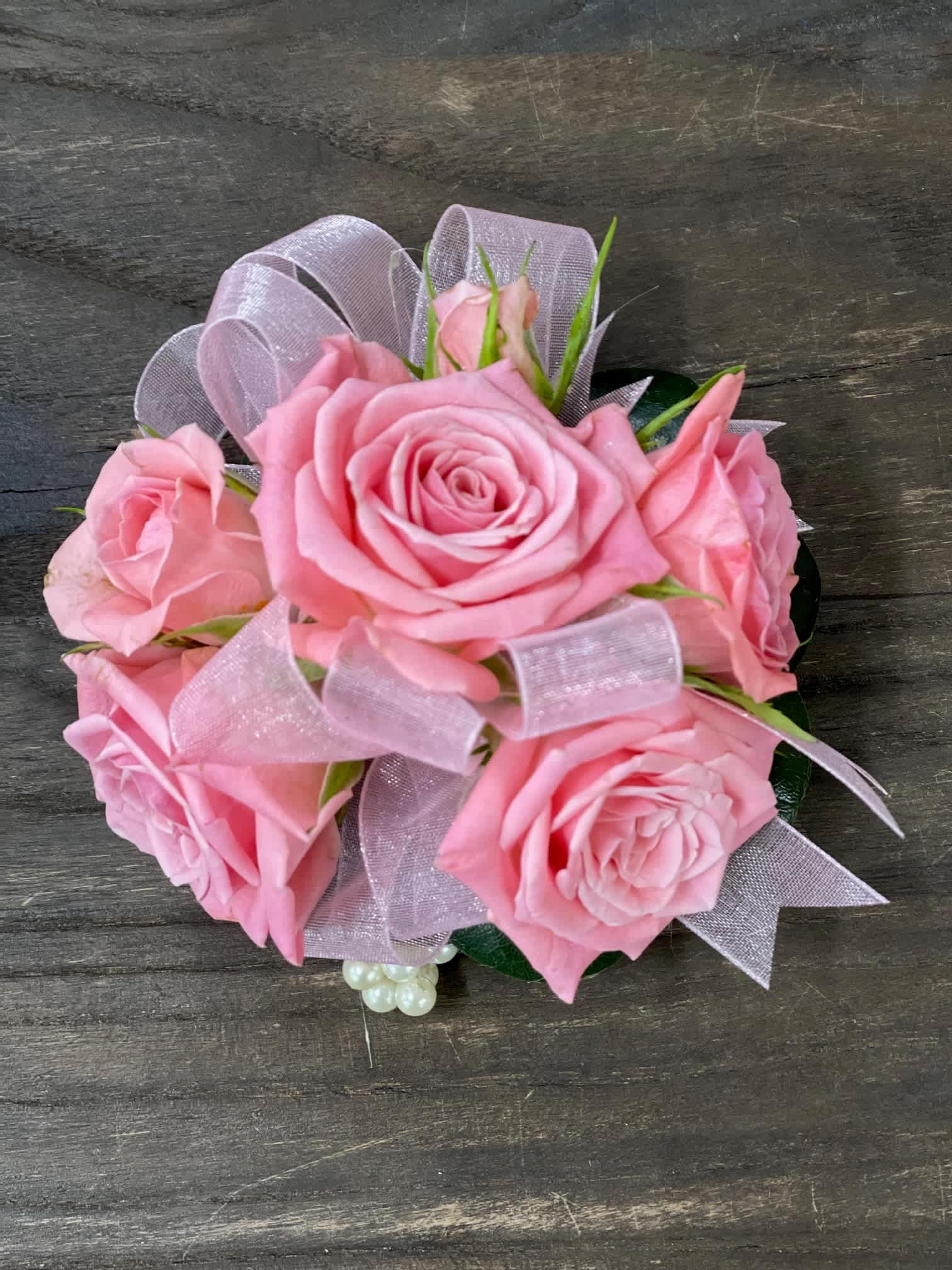 Pink rose bouquet with sheer ribbon on a dark wood surface
