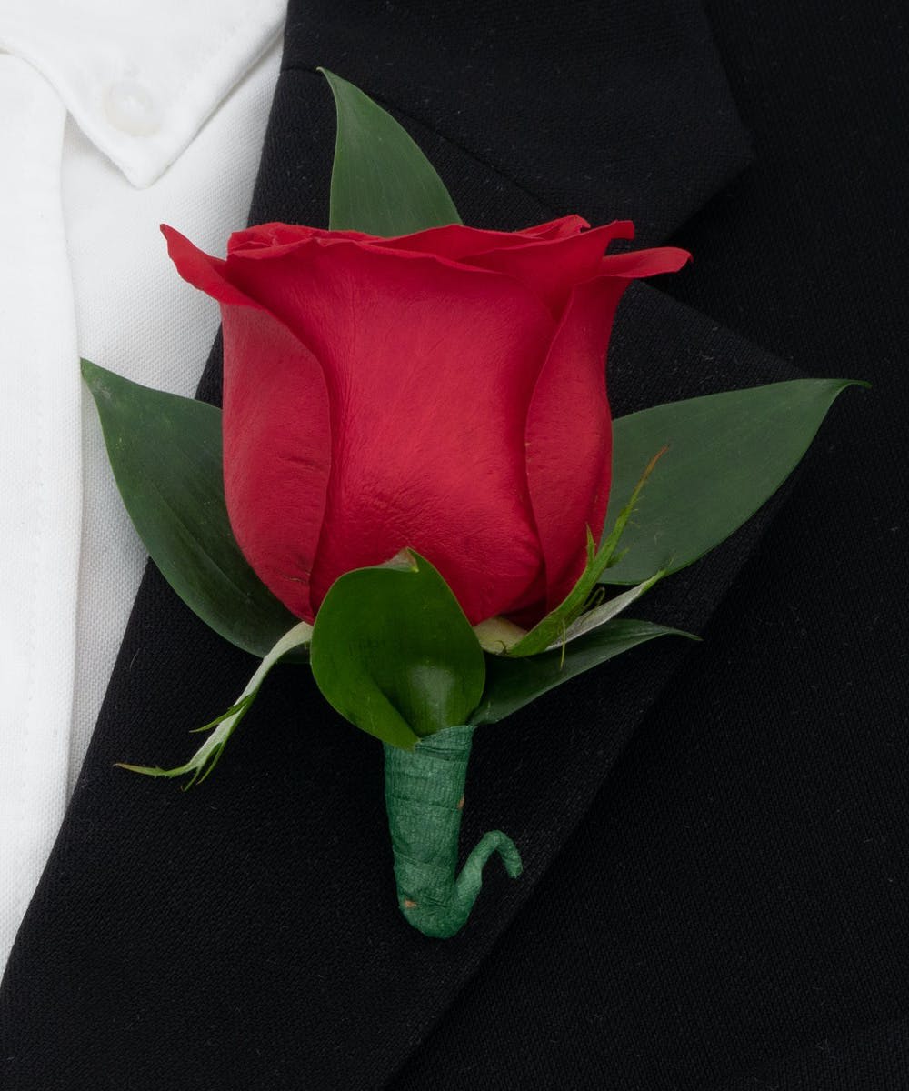 Red rose boutonniere with green leaves on a black suit lapel