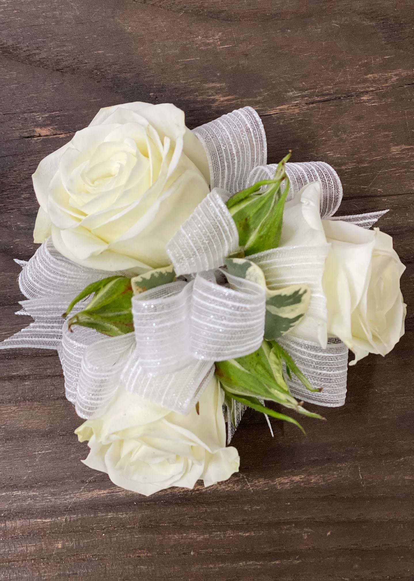 White rose corsage with sheer ribbon on a wooden surface