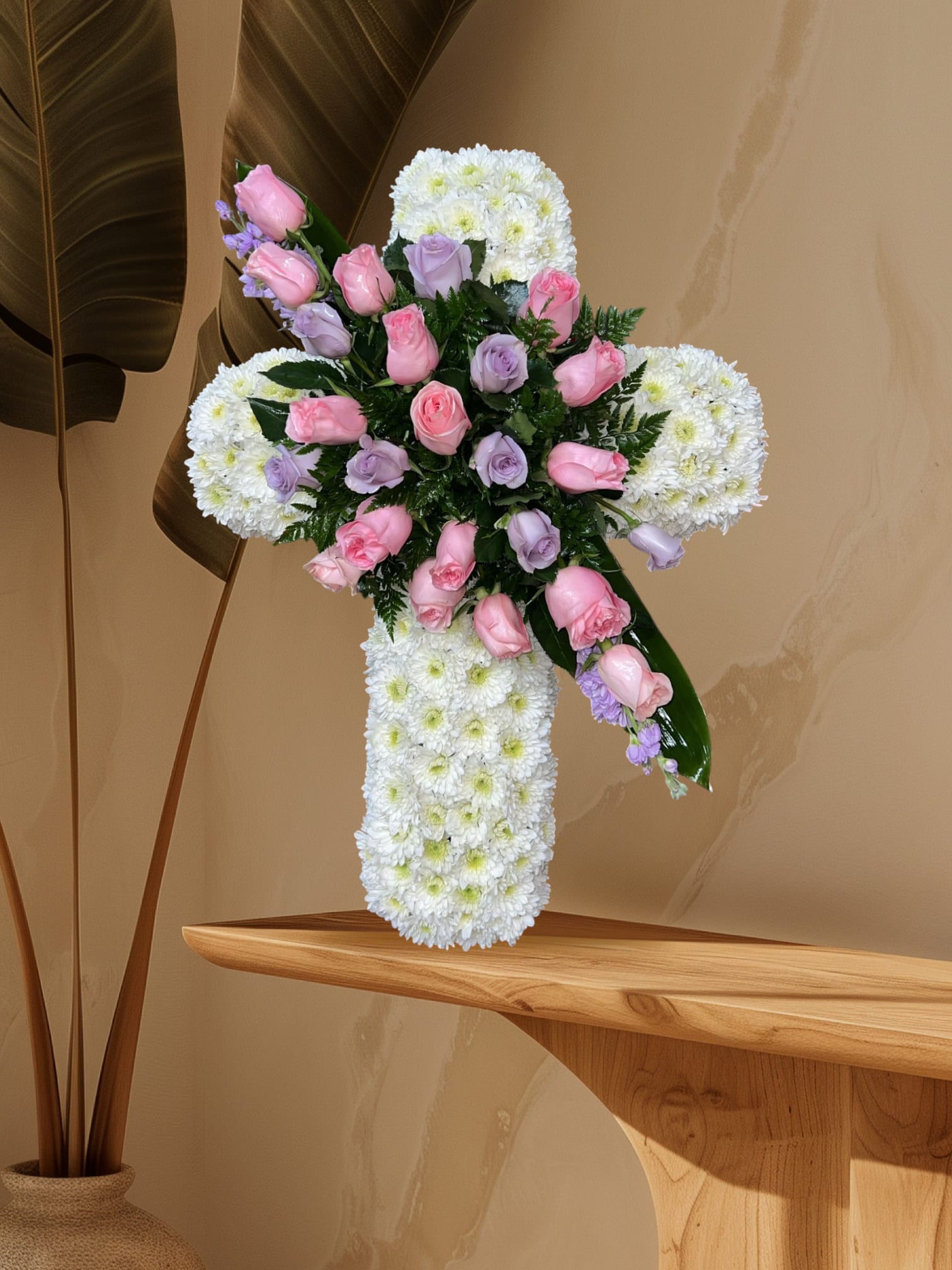 Heavenly Grace Cross - A delicate and elegant cross arrangement crafted with soft white chrysanthemums, symbolizing peace and purity, beautifully accented with pink and lavender roses for a touch of love and remembrance. This graceful tribute offers comfort and honors a life with gentle beauty and heartfelt sympathy.
