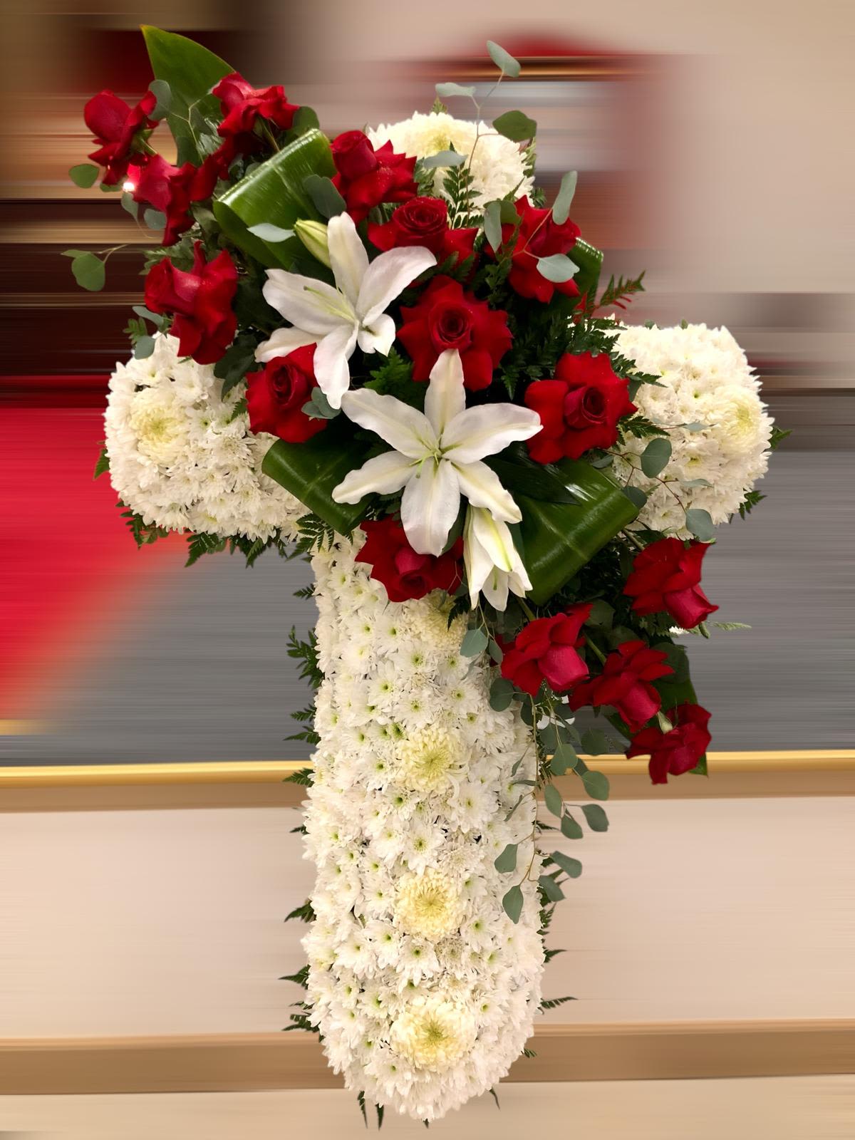 Crimson Devotion Cross - A striking cross arrangement featuring pure white chrysanthemums as the foundation, beautifully adorned with vibrant red roses and elegant white lilies. Accented with lush greenery, this design symbolizes deep love, faith, and remembrance—offering a powerful and heartfelt tribute to honor a cherished life.