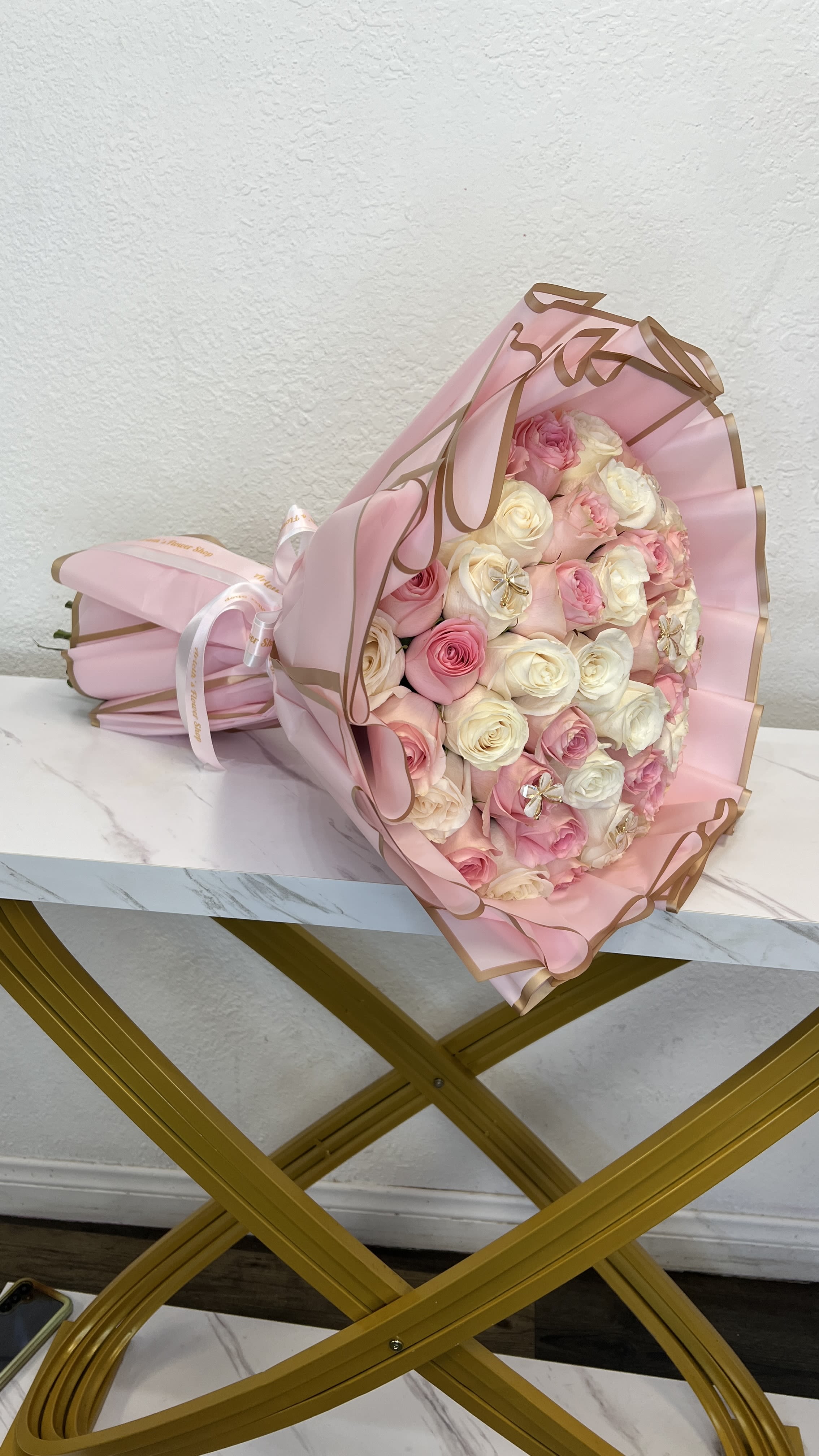 Pink and white rose bouquet wrapped in pink paper with gold trim