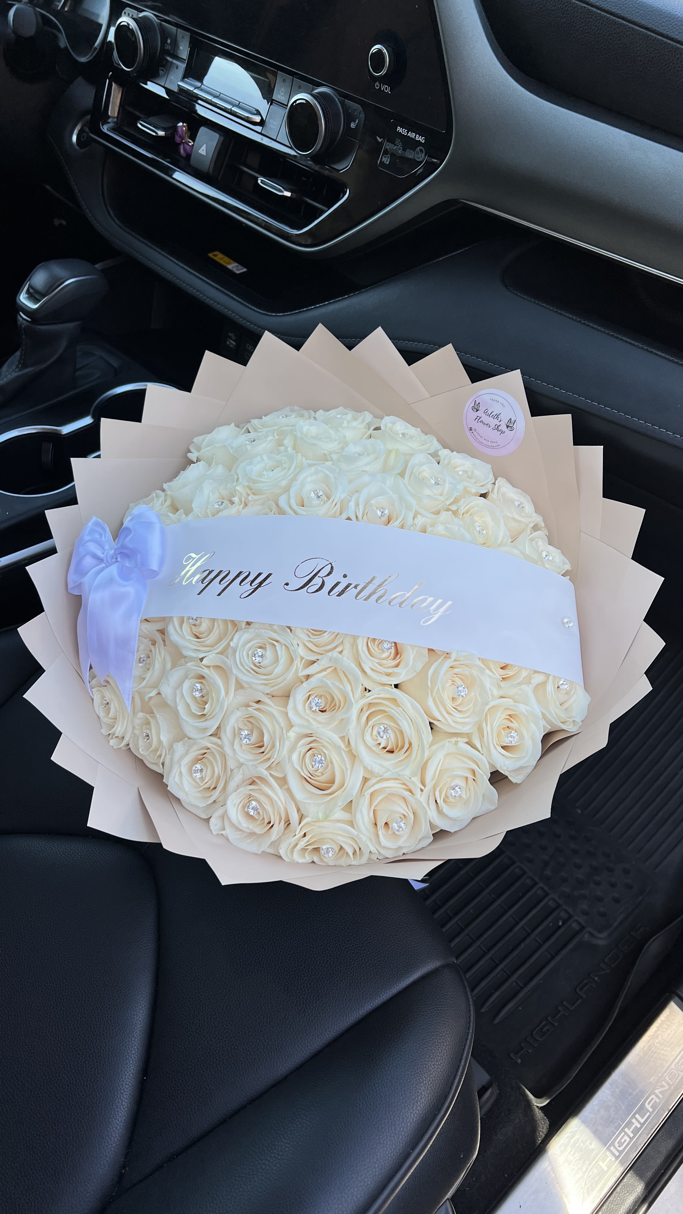 Cream rose bouquet with a Happy Birthday ribbon in a car seat