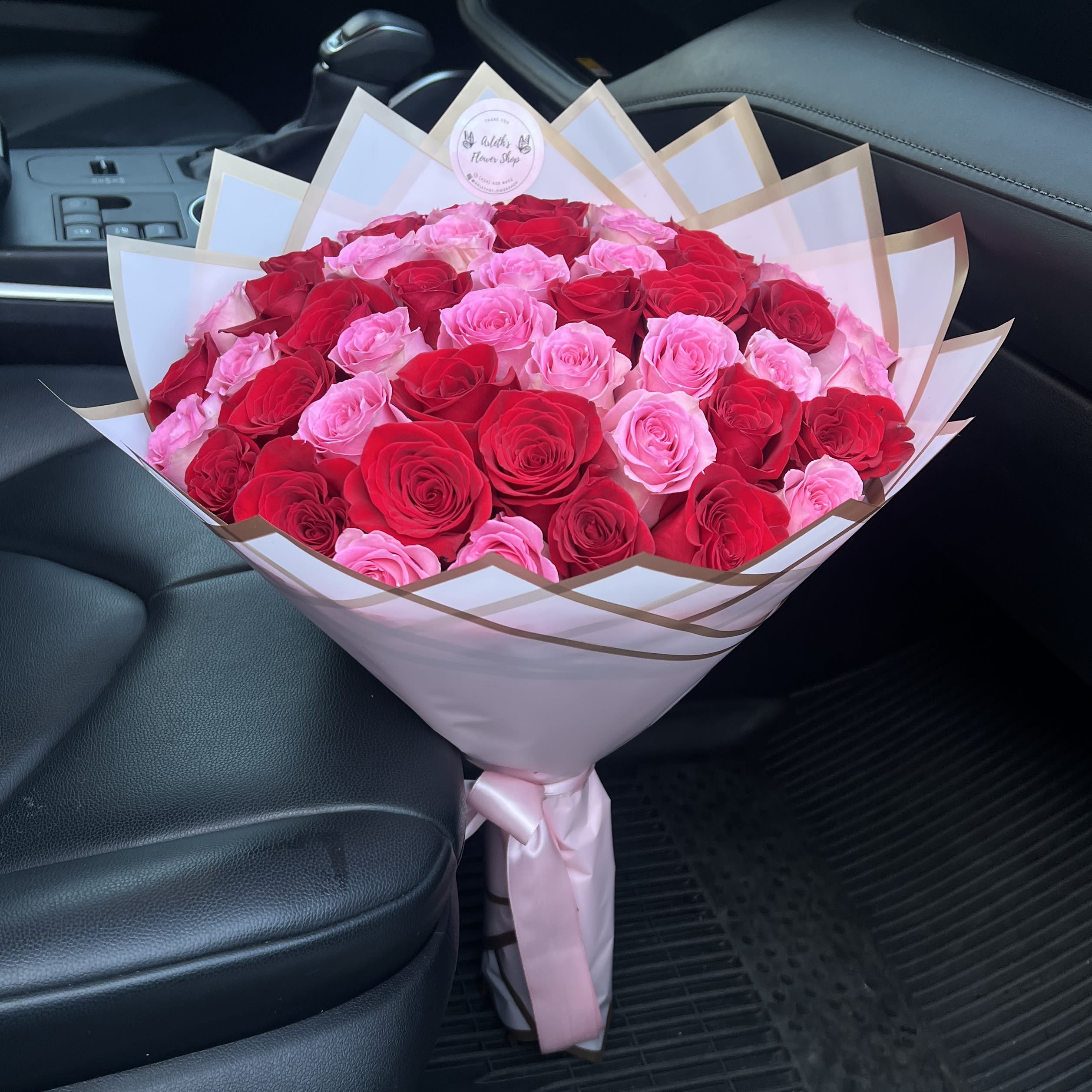 Large bouquet of pink and red roses wrapped in white paper
