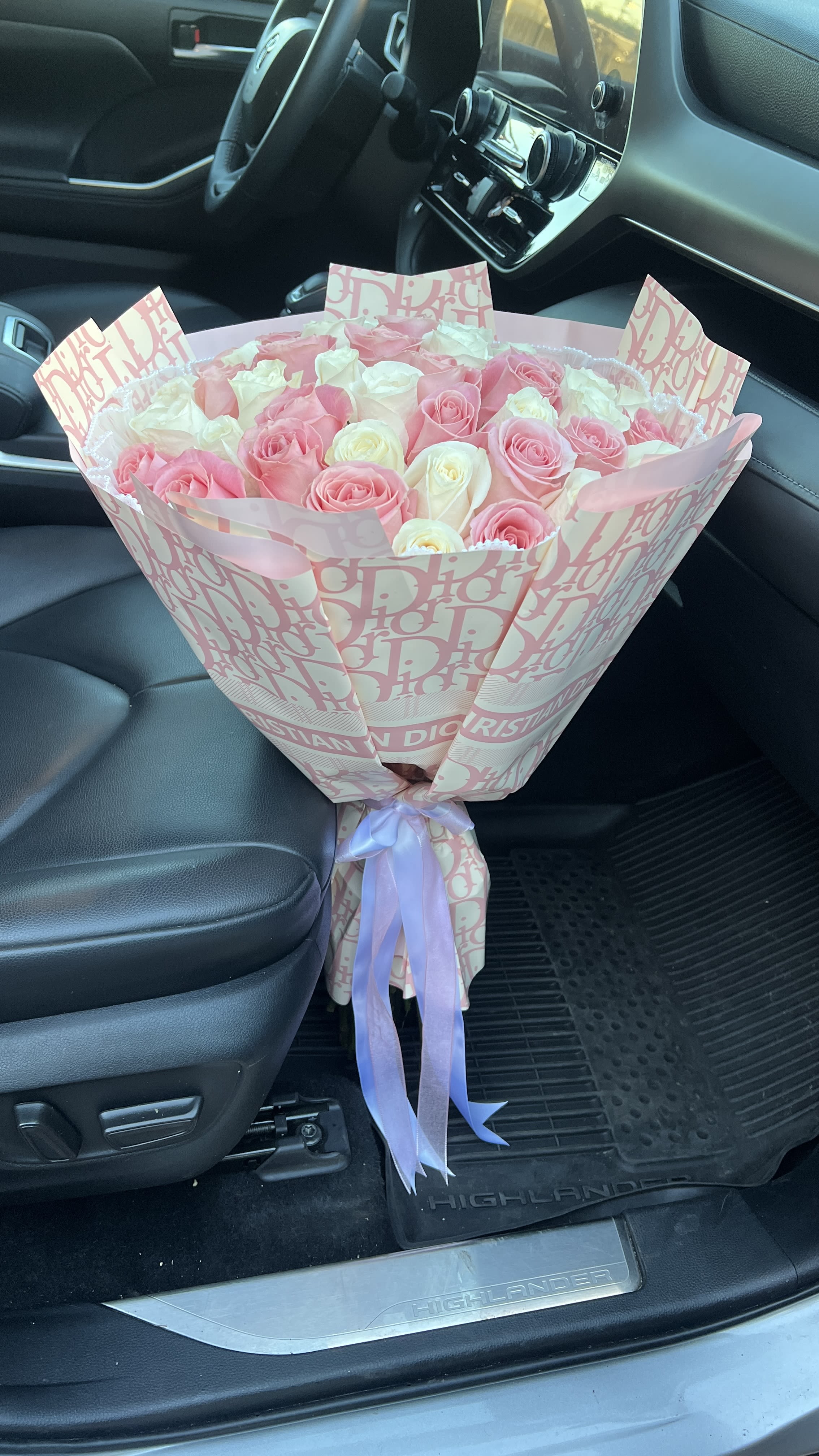 Pink and white rose bouquet wrapped in patterned paper with a ribbon