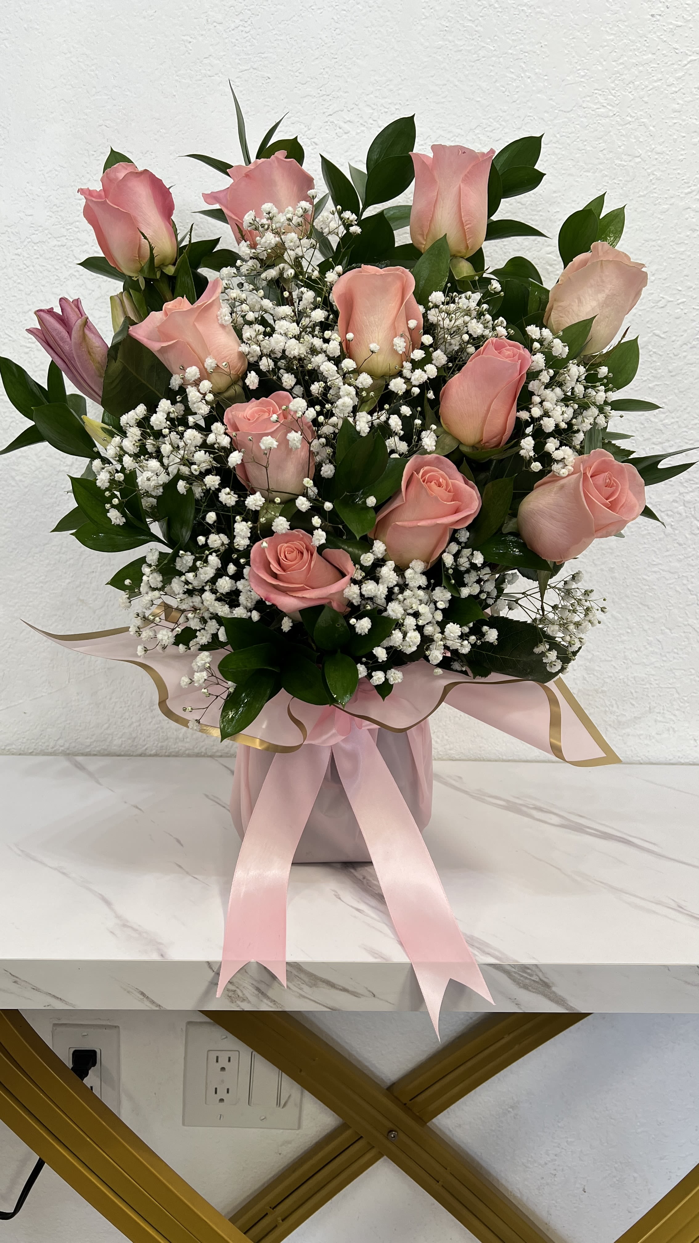 Pink roses and white baby's breath arranged in a pink box with ribbon.