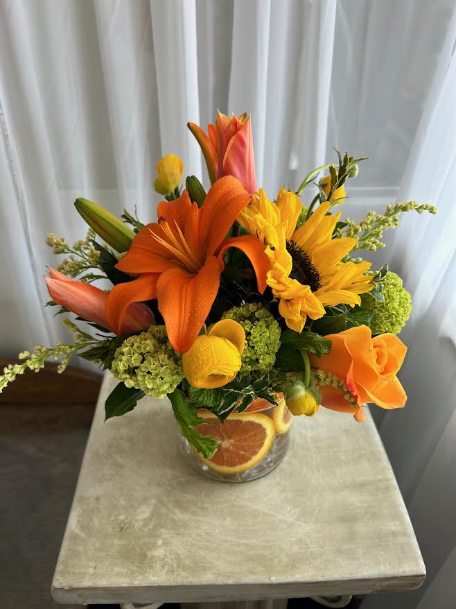 Orange and yellow floral arrangement in a clear glass vase