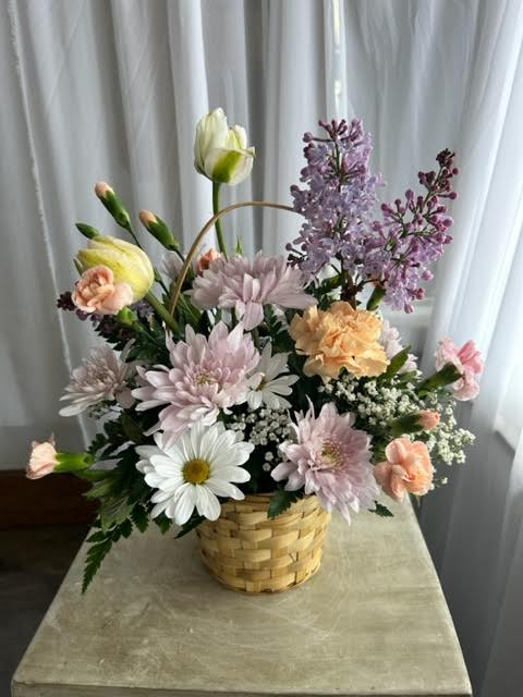 Basket arrangement of pastel flowers with daisies and lilac blooms