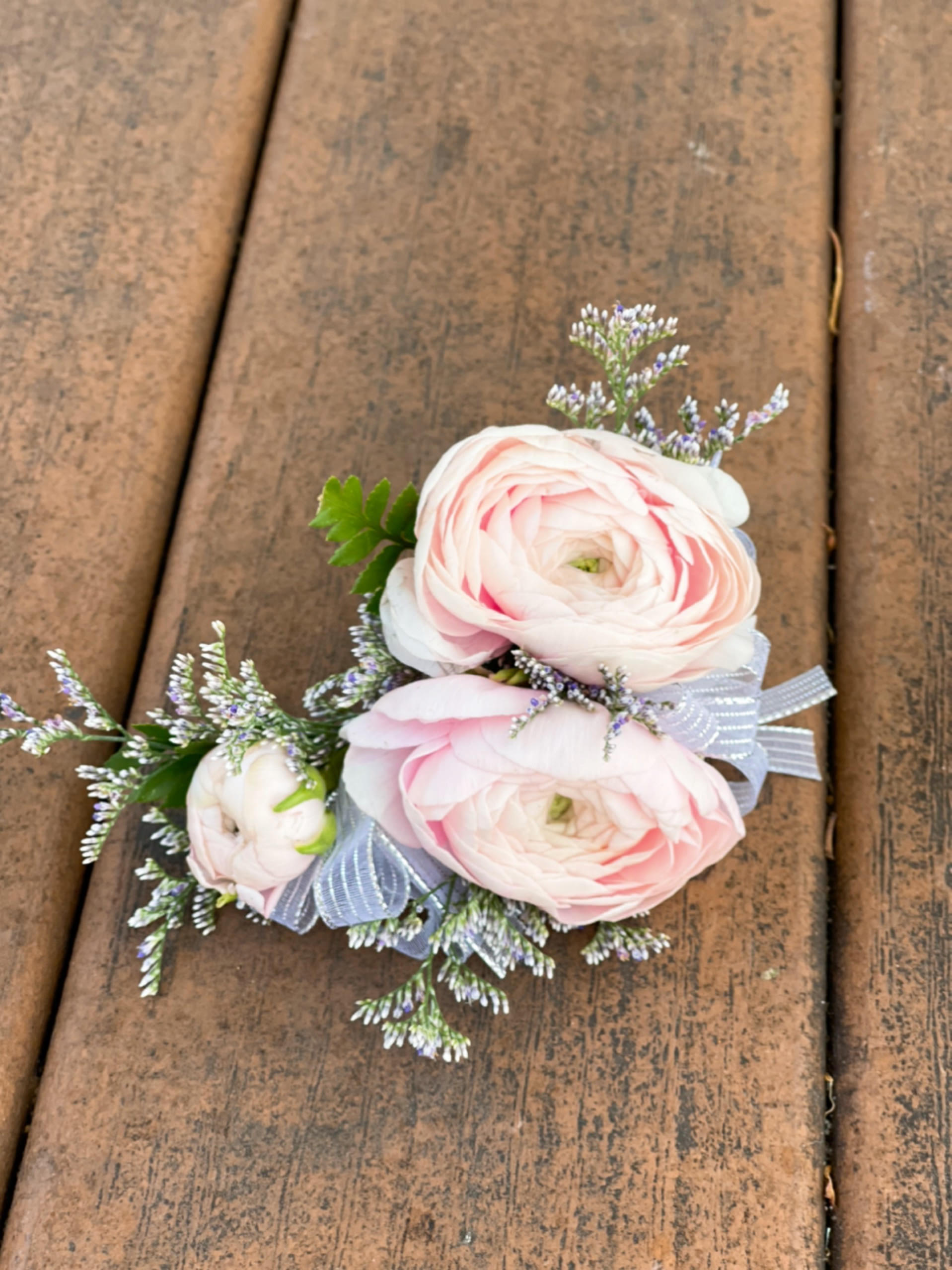 Small corsage with pale pink flowers and a ribbon bow
