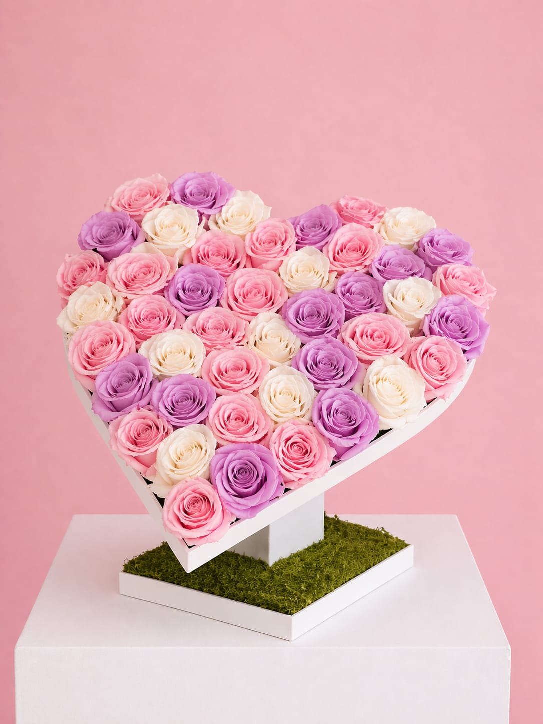 Eternal Bloom Heart – Mother’s Day Edition - Celebrate Mom with our Eternal Bloom Heart, a stunning floral display designed on a modern wooden heart stand. This one-of-a-kind arrangement features a curated blend of soft pink, ivory, and lavender roses, carefully placed into floral foam for a full, luxurious look. The base is finished with natural moss, adding an elegant garden touch that makes this piece feel both fresh and timeless.  Perfect as a statement gift and home décor piece, this design is created to impress from every angle—thoughtful, unique, and made with love for Mother’s Day.  Includes approx. 45–60 roses. Rose tones may vary slightly based on availability.