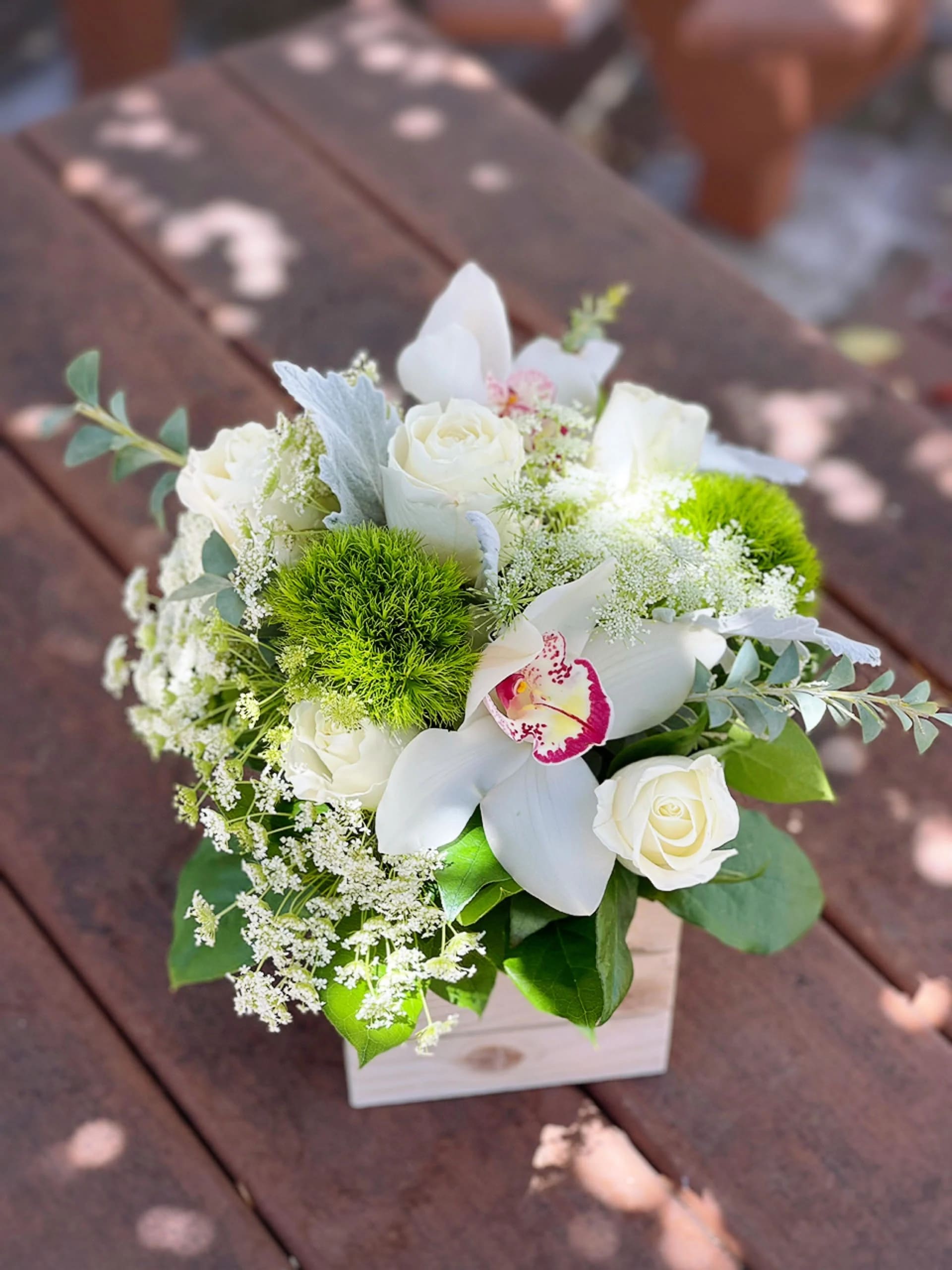 White roses and orchids in a small wooden box