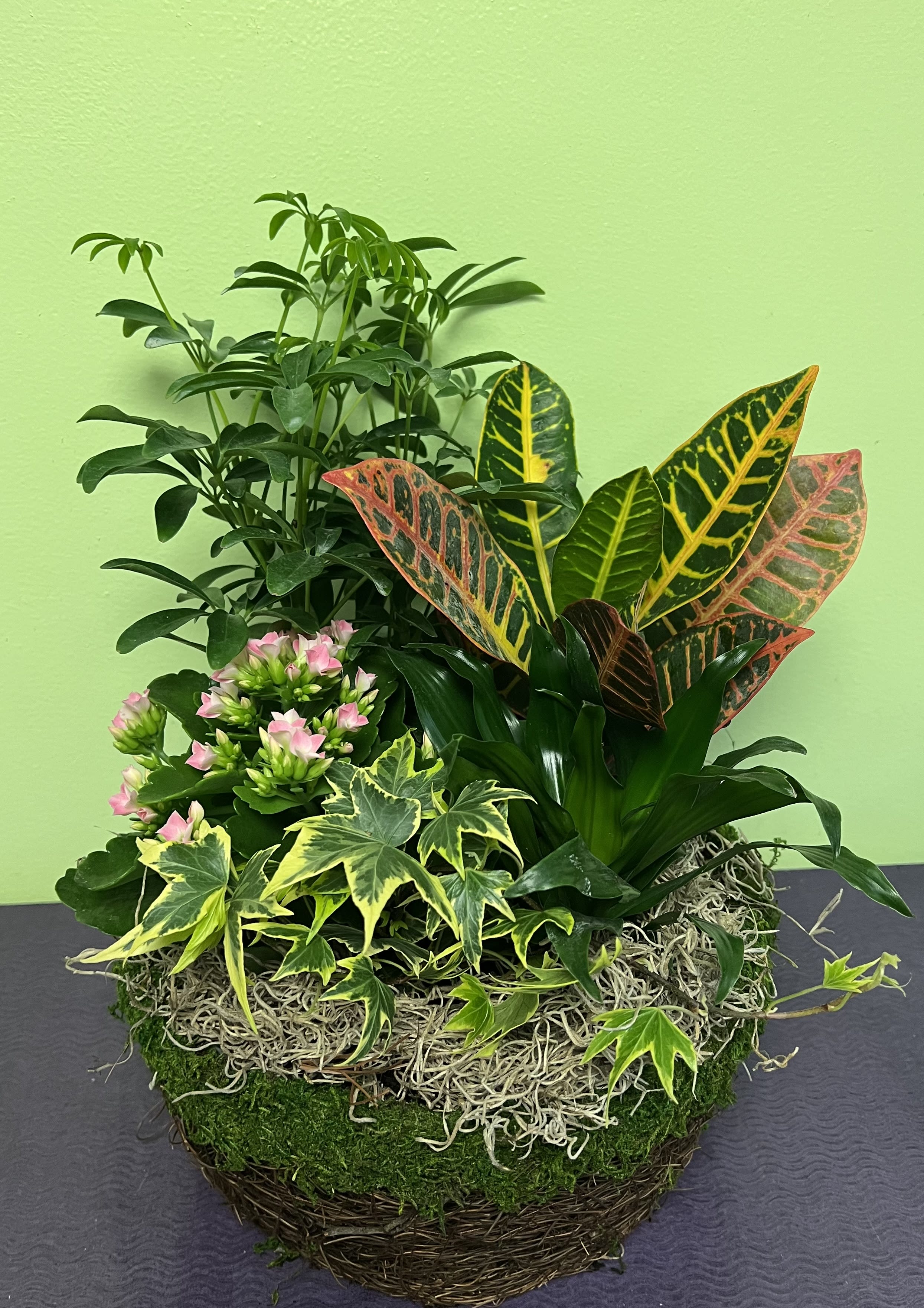 Mixed potted plants with pink flowers in a woven basket