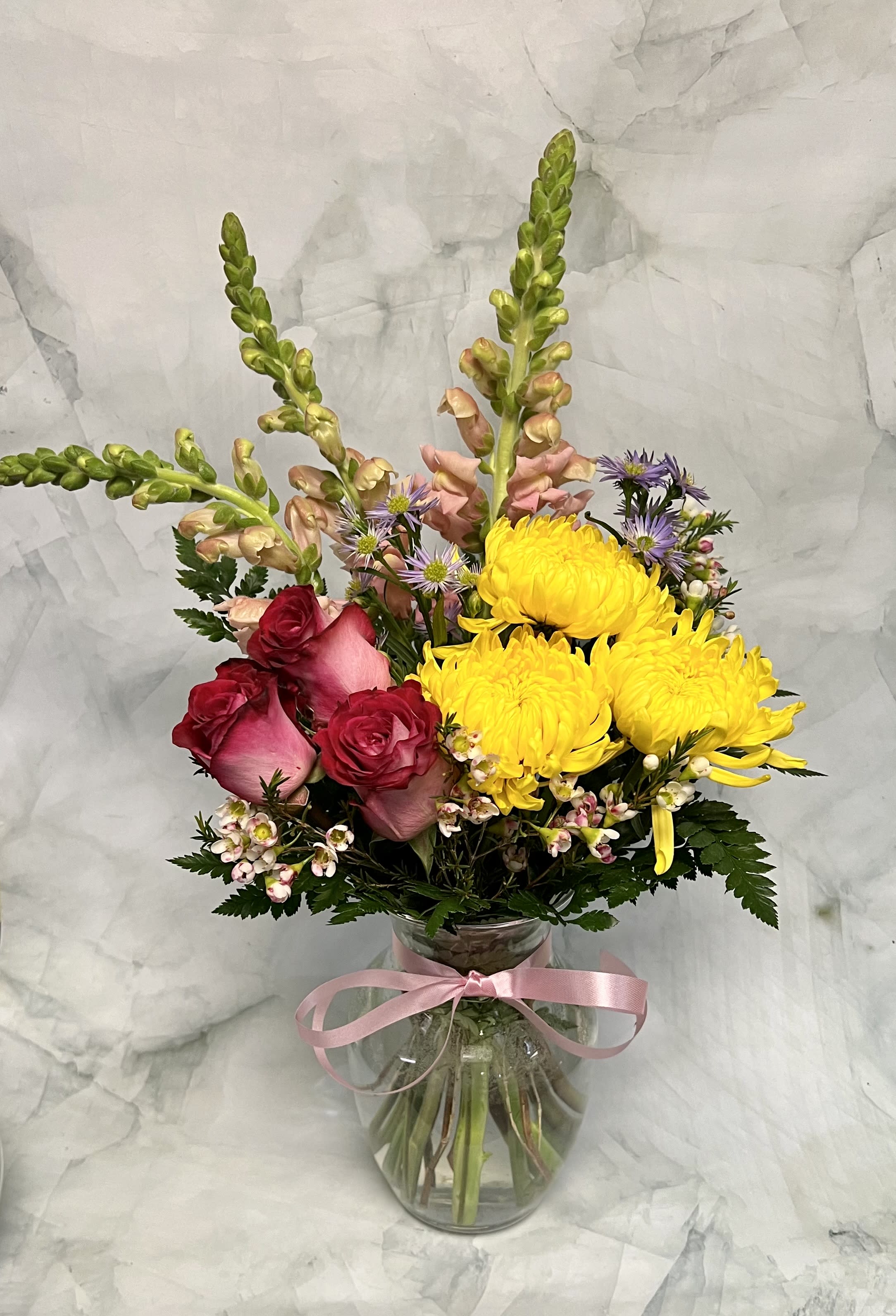 Mixed bouquet with yellow chrysanthemums, pink roses, and a glass vase tied with ribbon