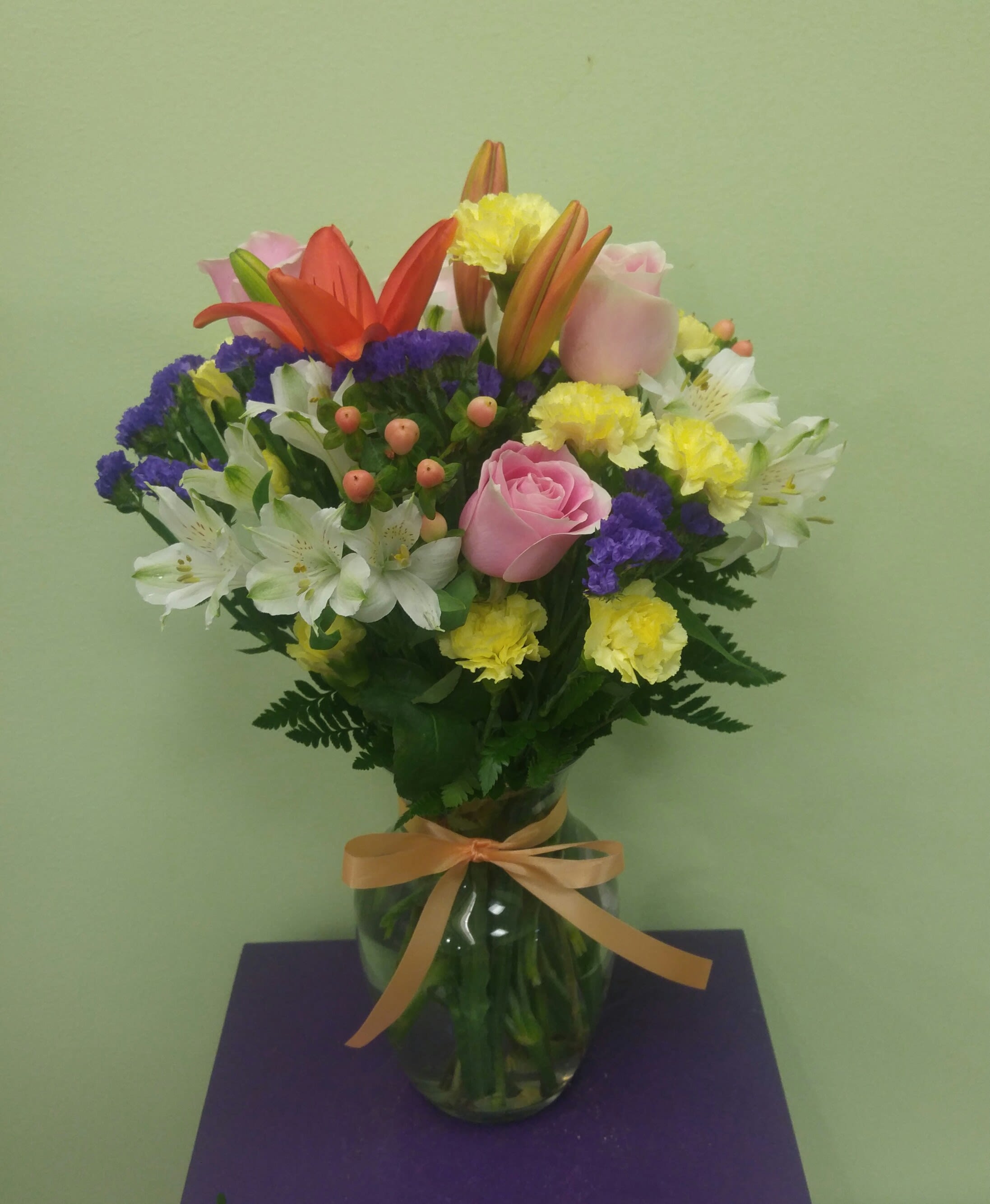 Mixed bouquet of lilies, roses, and carnations in a glass vase