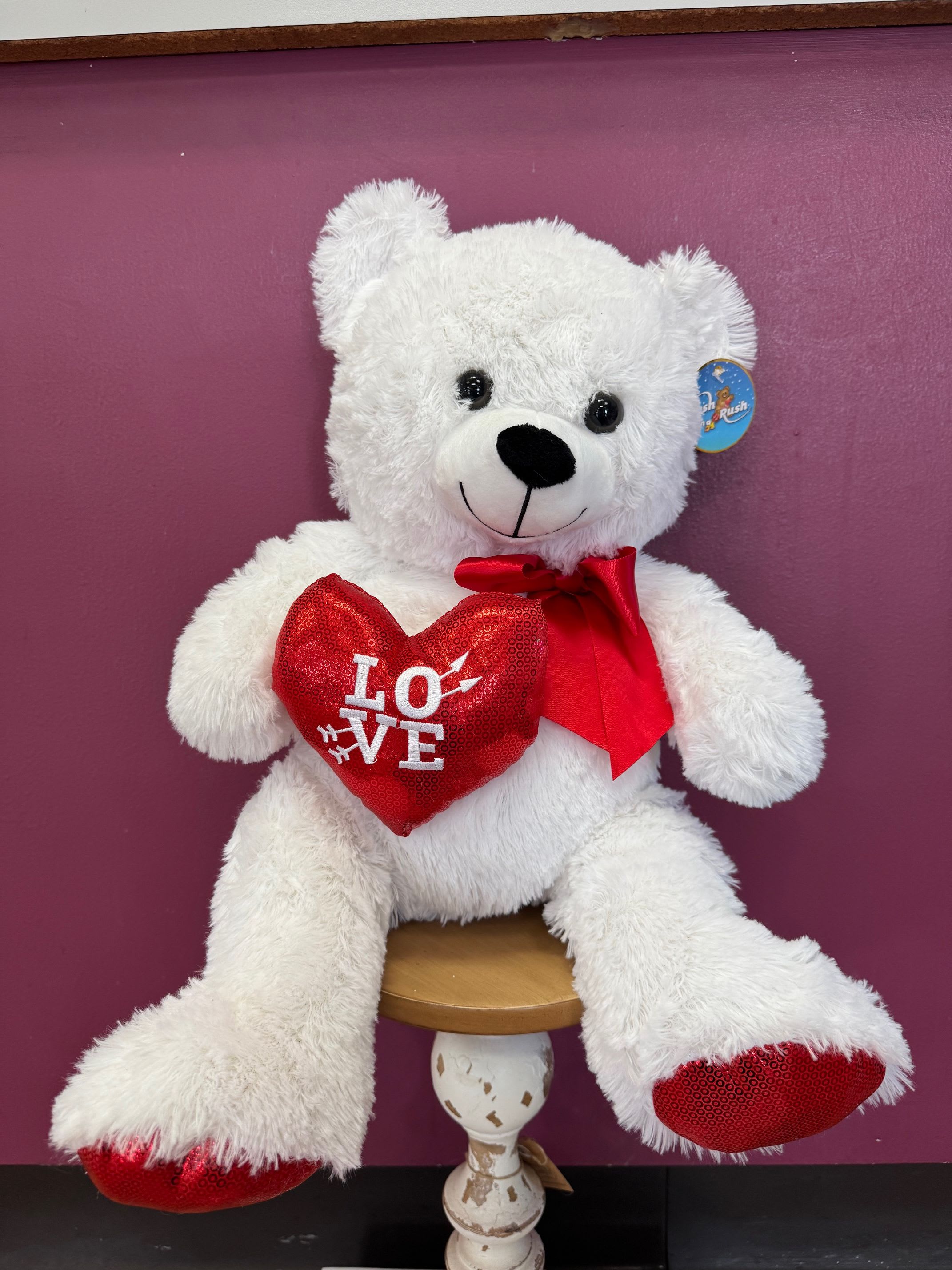 18" White bear holding a red Heart - A cuddly 18" white teddy bear holding a red fabric heart is a playful and affectionate gift for Valentine's Day or to say "I love you" any day.   The bear arrives seated and ready to display, about 18 inches tall, with a plush texture that invites hugs and a fabric heart that keeps your message on display. White, red, and touches of pink combine for a classic palette; the satin ribbon bow adds a polished finish. No watering or vase is needed, making it a low-maintenance, long-lasting token that complements flowers, roses or chocolates if you choose to pair it with additional treats.