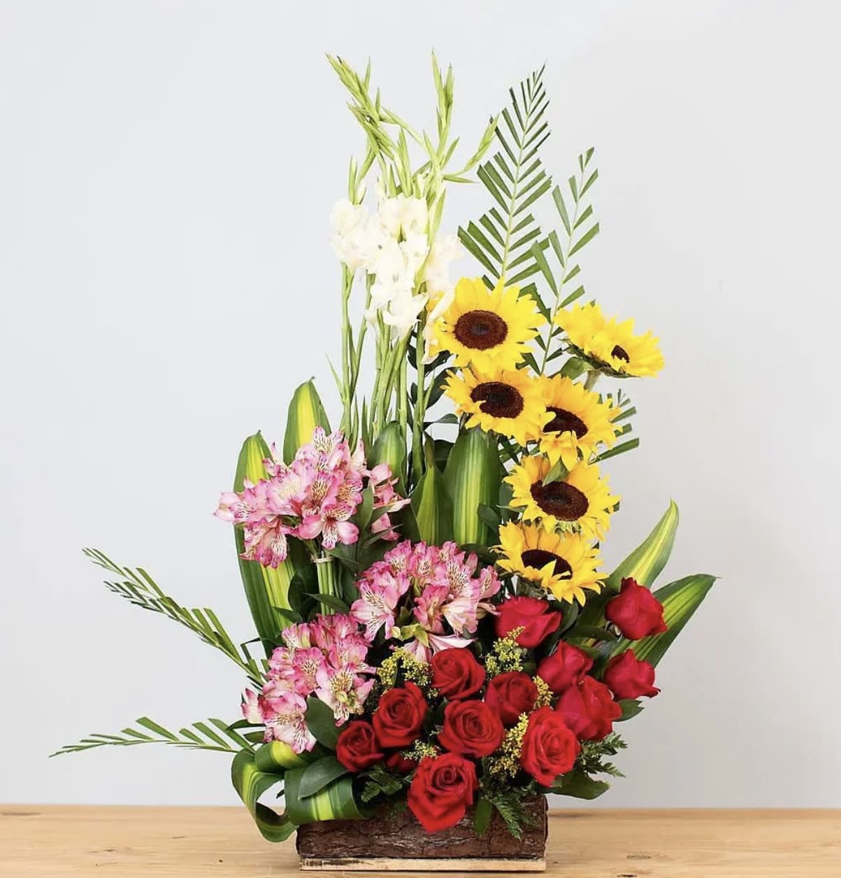 Tall mixed flower arrangement with red roses, pink alstroemeria, and sunflowers