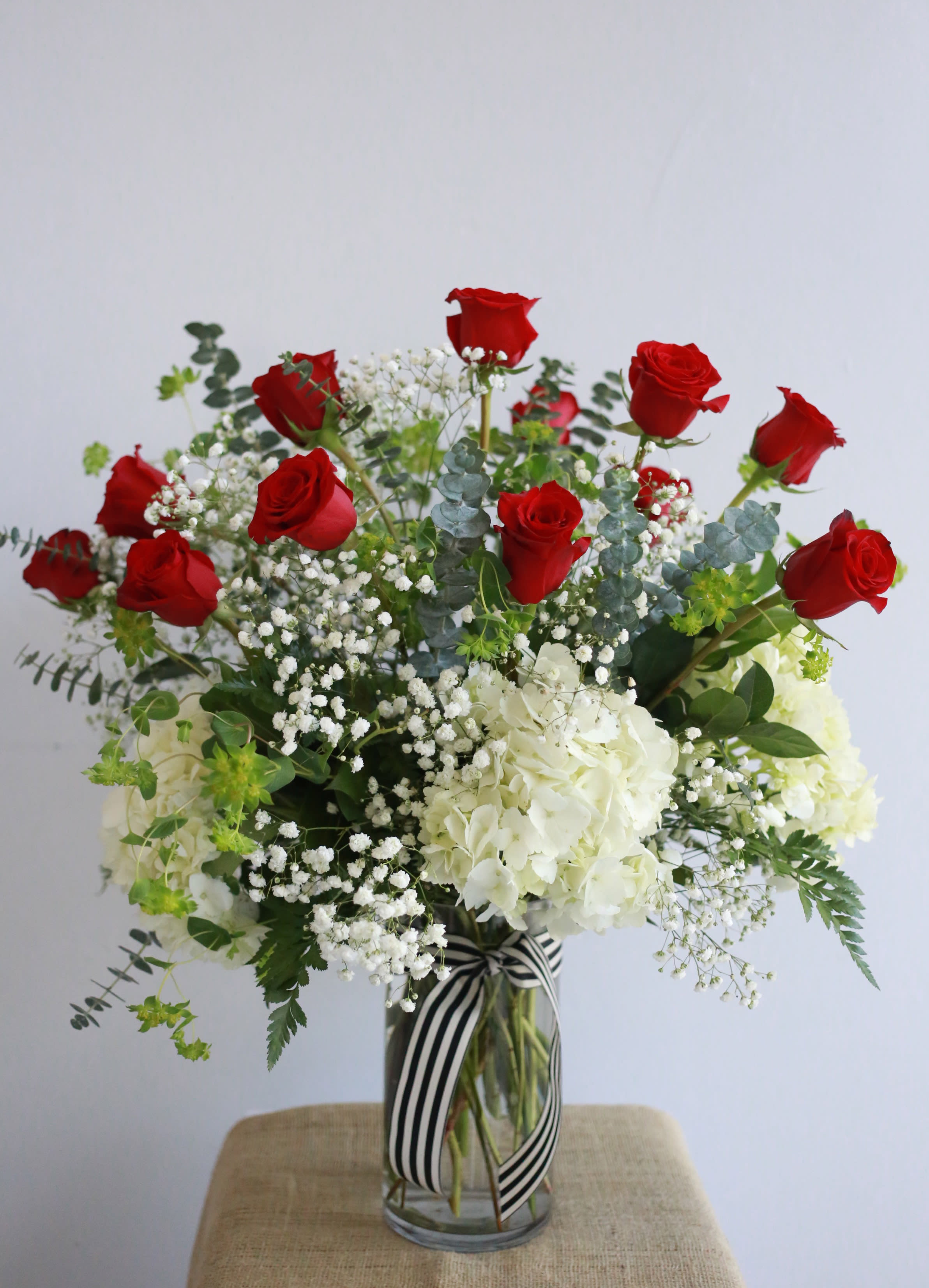 Love You To The Moon - Tall, Classy, Elegant.1 , 2, or 3 Dozen premium long stemmed roses, beautiful large white fluffy hydrangeas surrounding the base all around. Designed with a lush assortment of greenery and fillers. Simple and classic