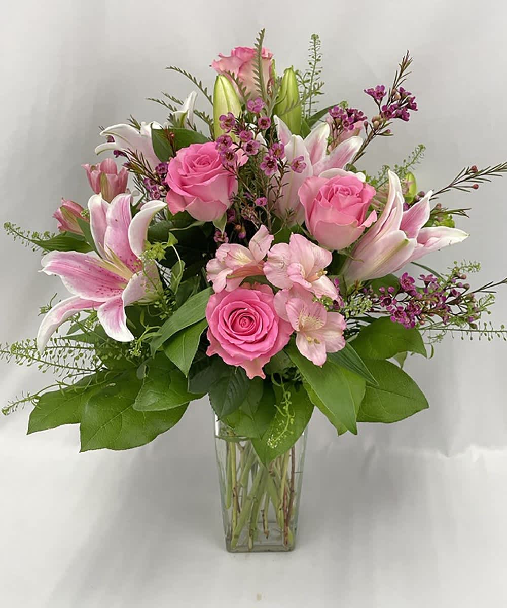 Pink roses and lilies arranged in a clear glass vase