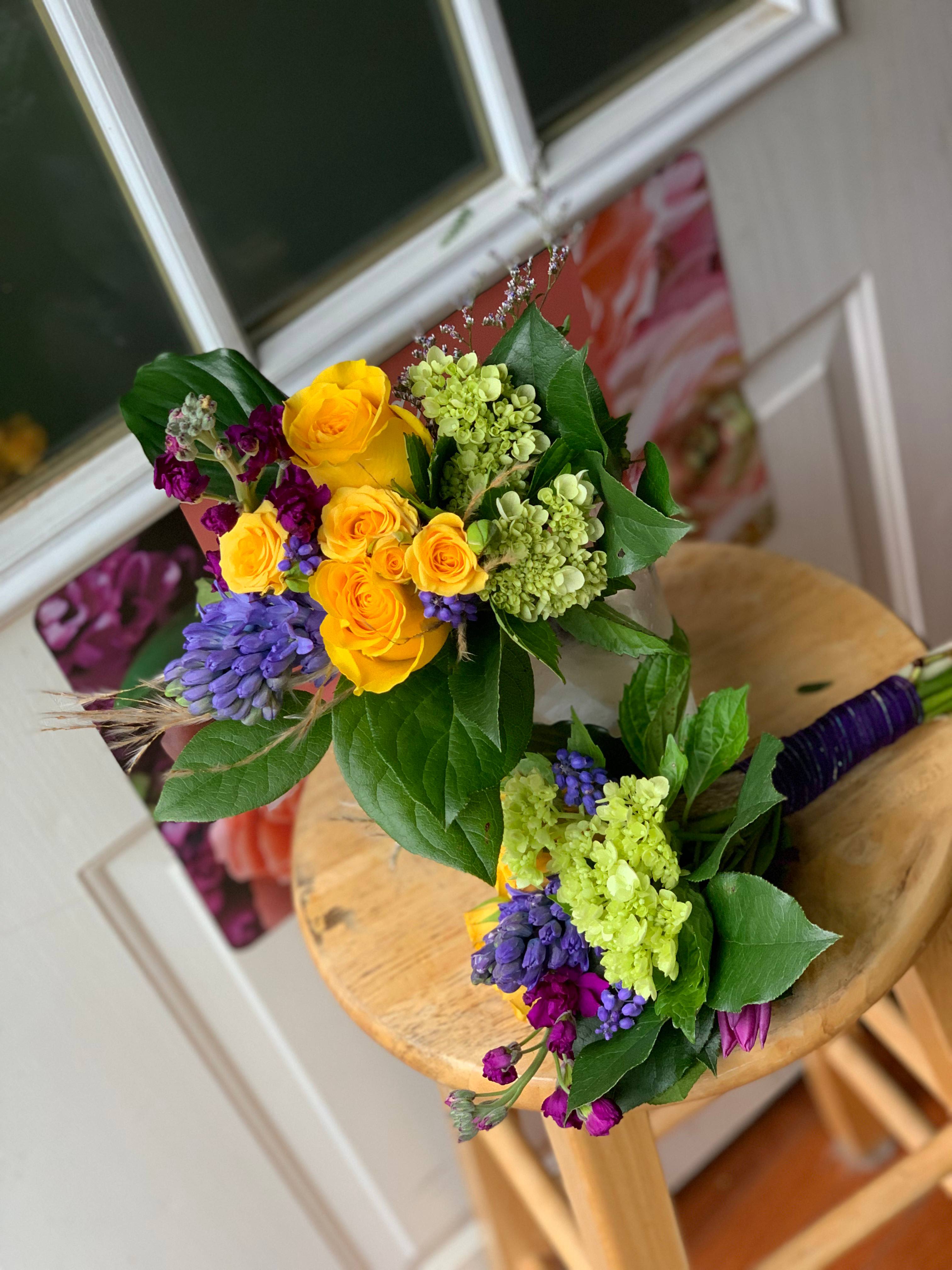 Two colorful hand-tied bouquets with yellow roses and purple flowers