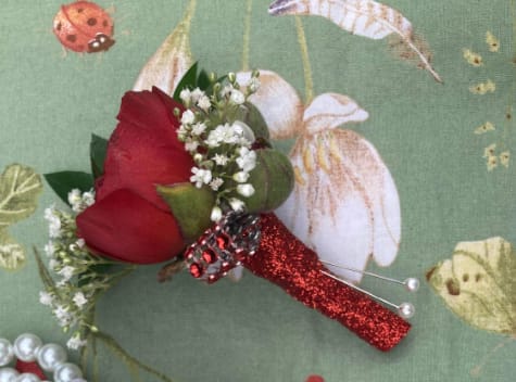 Red rose boutonniere with baby's breath and a glittery red handle