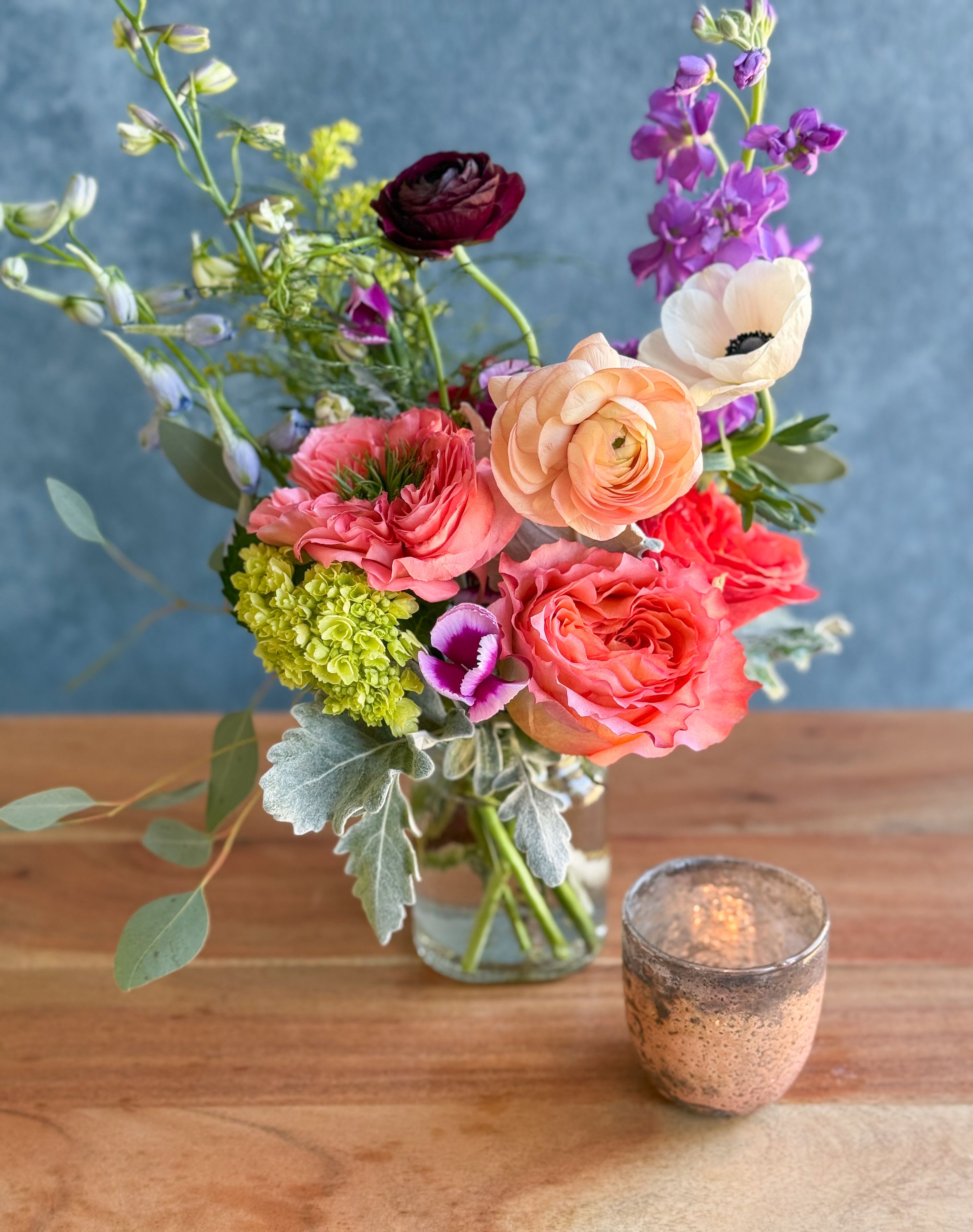 Mixed bouquet in a glass vase with pink, peach, purple, and white blooms