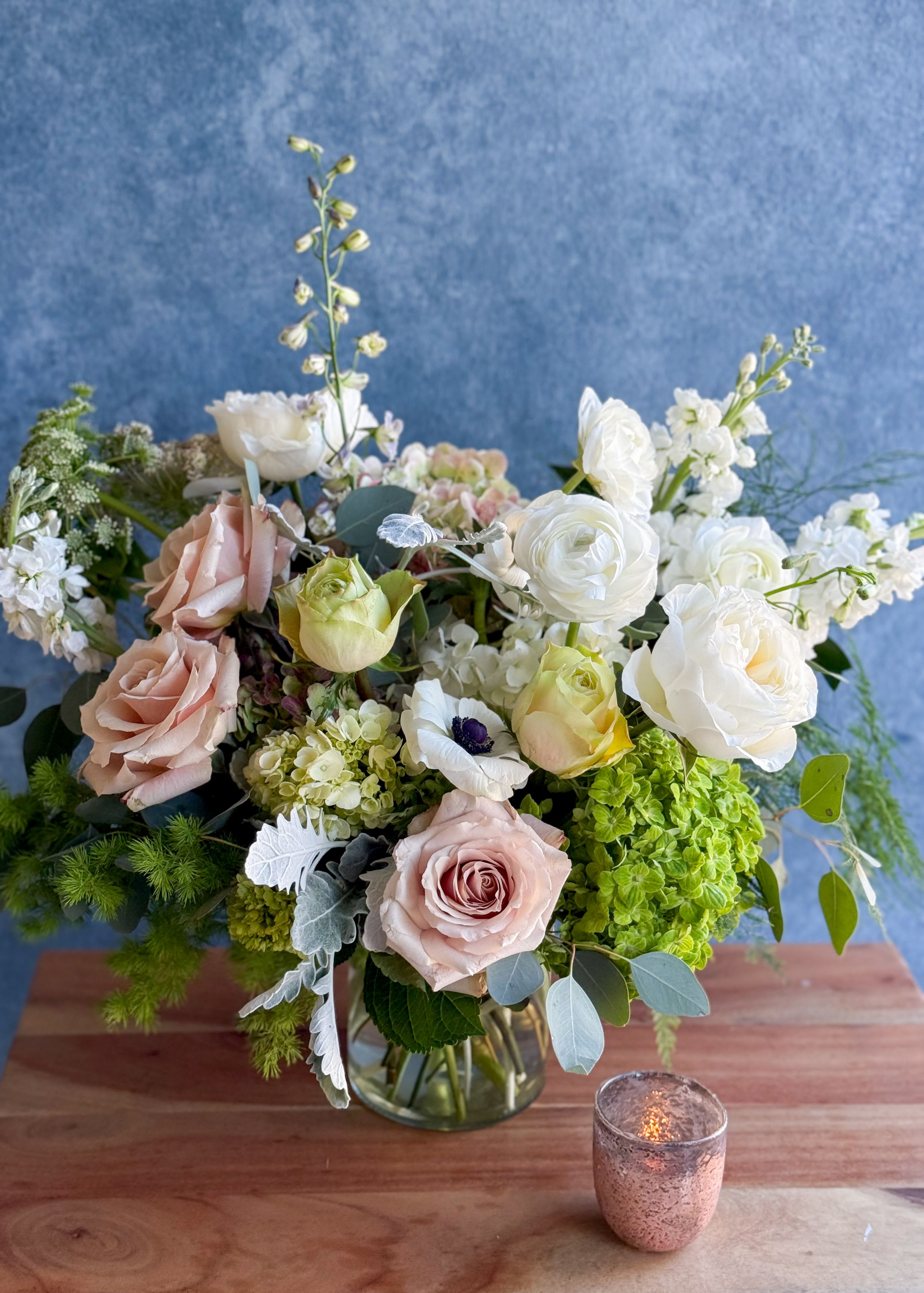 Mixed bouquet of pale roses and white blooms in a glass vase