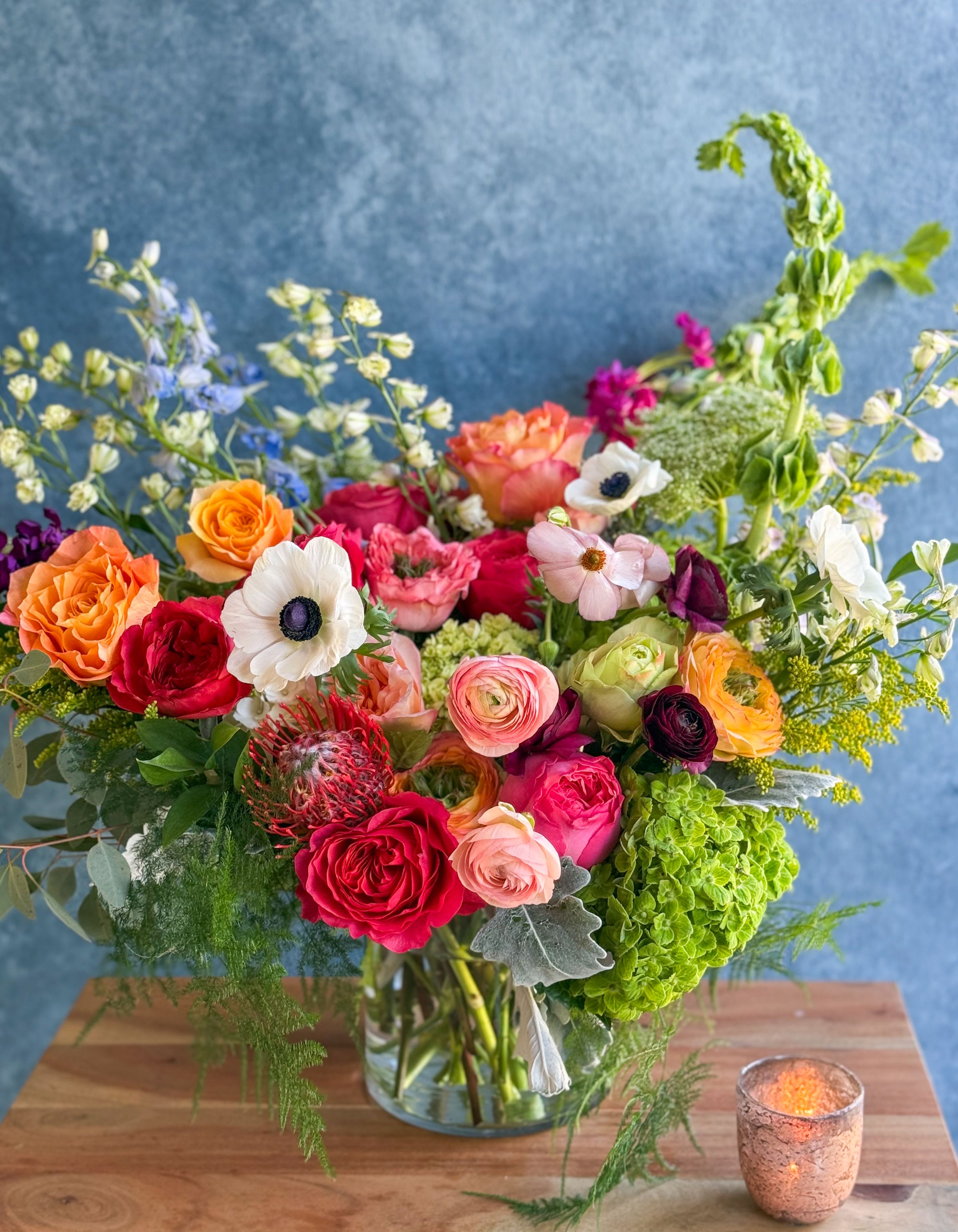 Mixed bouquet of colorful flowers in a glass vase on a table