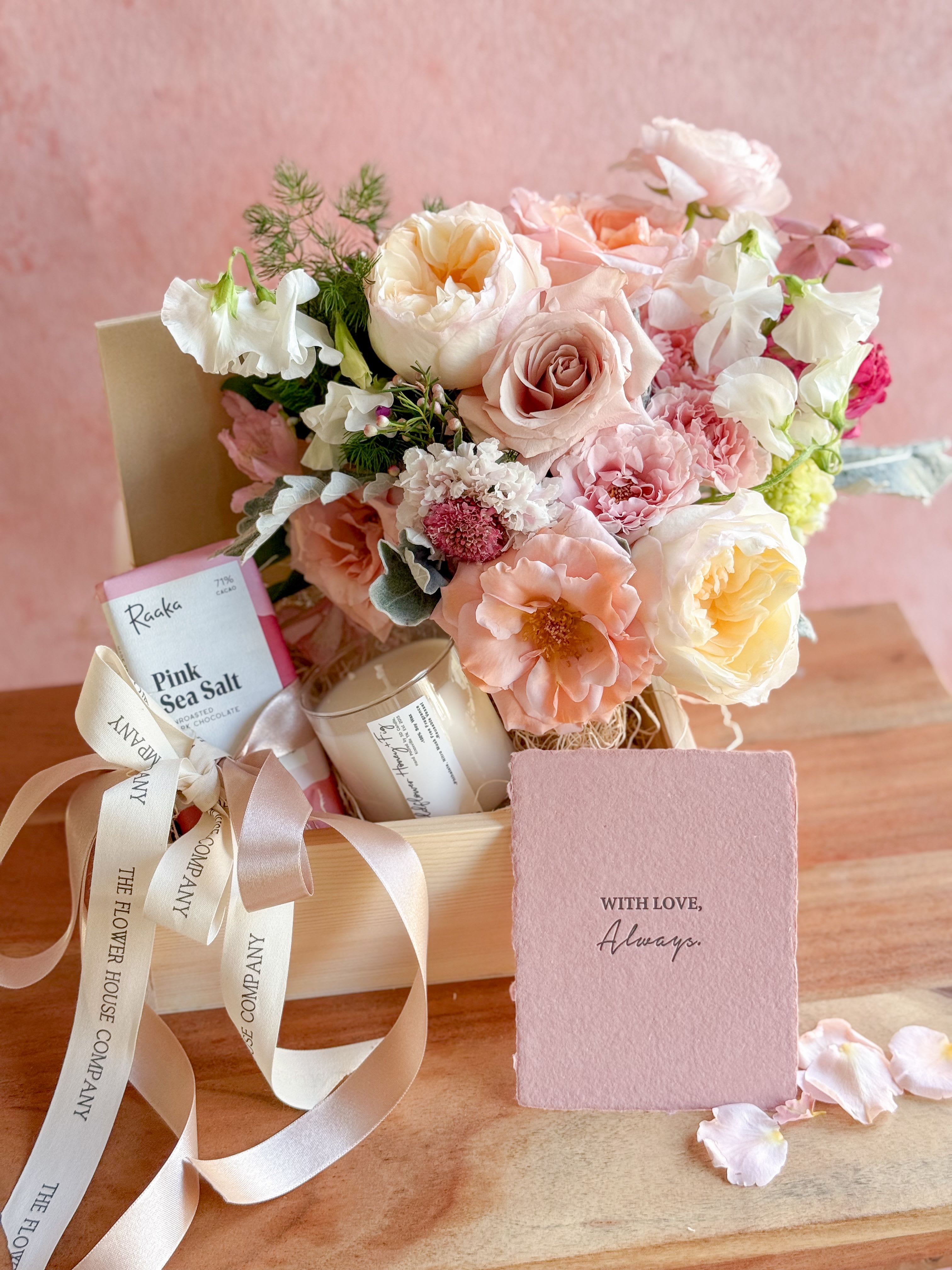 Pastel bouquet in a gift box with chocolates, a candle, and a card