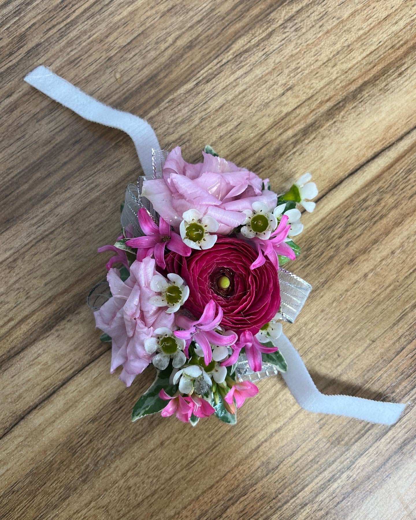 Small pink floral wrist corsage with ribbon ties