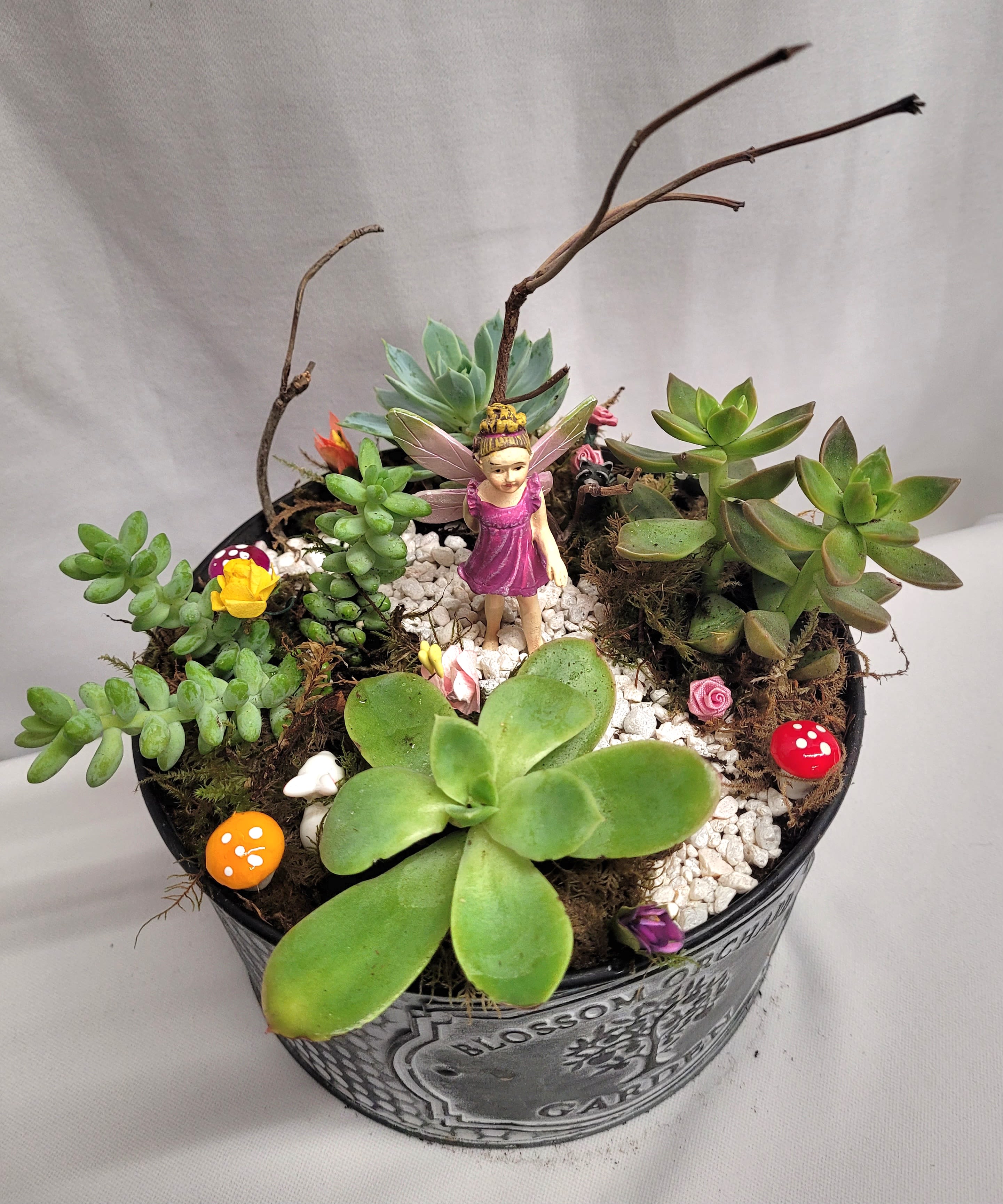 Succulent arrangement in a metal pot with a small fairy figurine