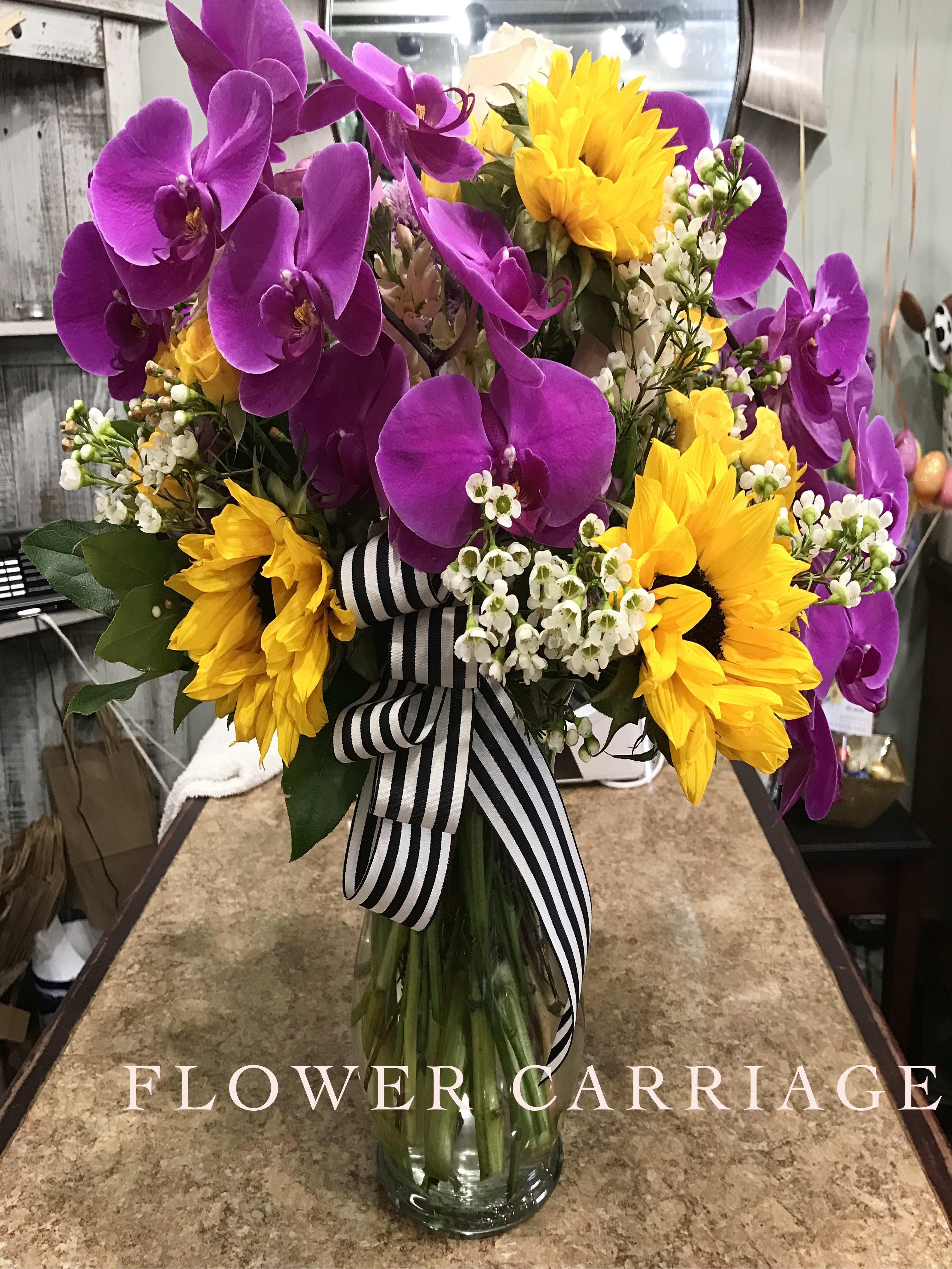 Elegant and Sunny By Flower Carriage - Who said Orchids and Sunflowers don't look good together? Clear Glass Fluttered vase with and accent of black and white striped ribbon. 