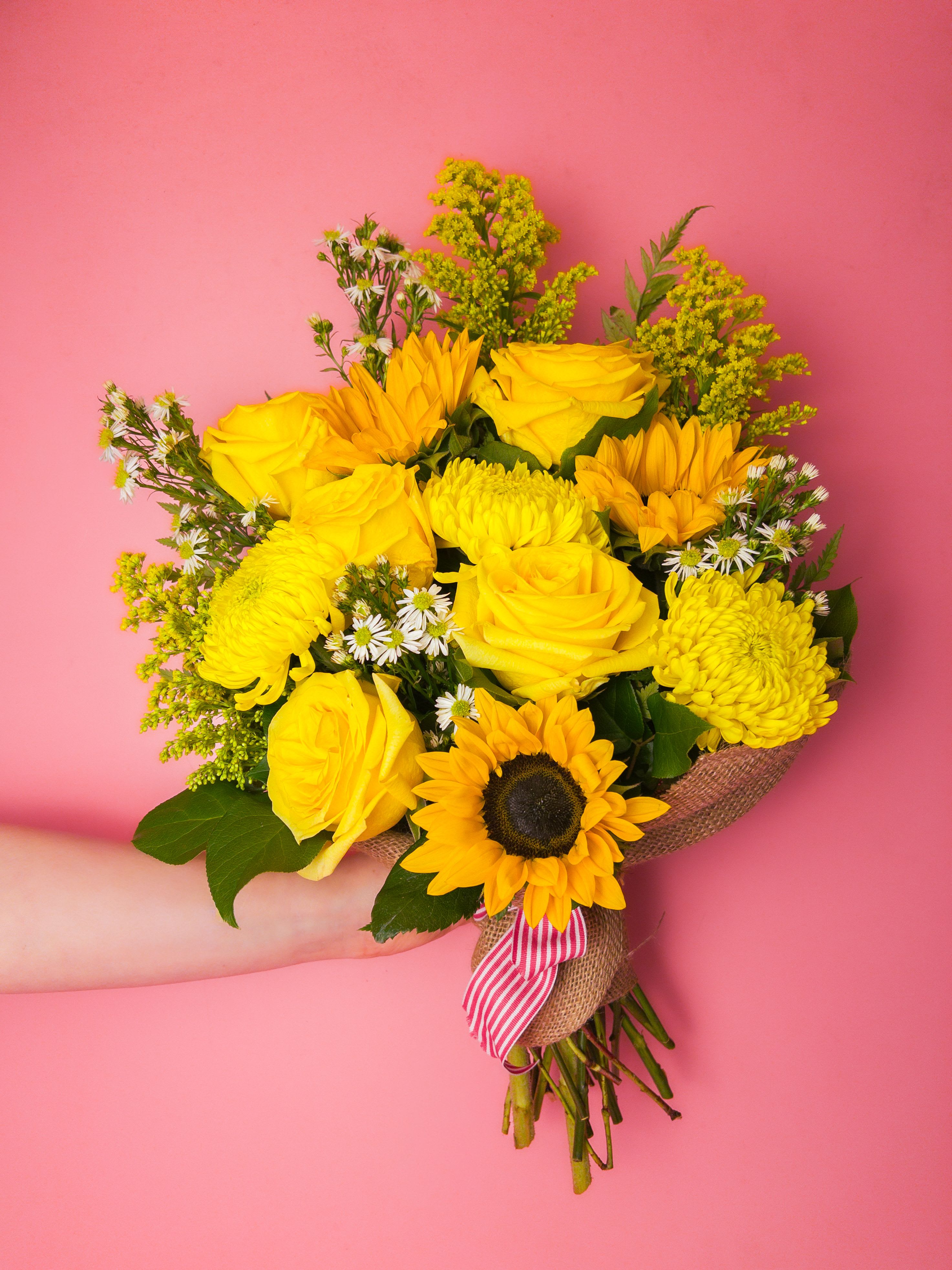 Yellow bouquet with roses, sunflowers, and mums tied with a striped ribbon