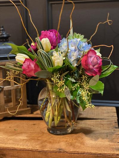 Mixed bouquet of pink, white, and blue flowers in a glass vase