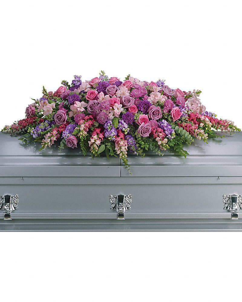 Pink and purple floral casket spray on a gray casket