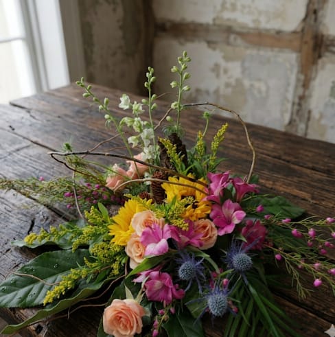 The Wild at Heart - The Wild at Heart | Mother’s Day Flower Delivery in Tumwater  Celebrate Mom with the untamed beauty of the Pacific Northwest. The Wild at Heart is a vibrant, wildflower-inspired arrangement featuring sunflowers, alstroemeria, larkspur, roses, and natural curly willow—bringing texture, movement, and a free-spirited feel to every stem.  Inspired by the wild landscapes of the PNW, this design blends bold color with organic elements for a look that feels fresh, natural, and full of life. The cheerful sunflowers and soft roses create a beautiful balance of warmth and romance, while larkspur and curly willow add height and that signature wild, airy style.  Perfect for Mother’s Day flower delivery in Tumwater, this arrangement is designed for moms who love something a little more natural, artistic, and unique. It also makes a thoughtful birthday gift, bringing a burst of color and joy into any space.  Each arrangement is handcrafted in a loose, gathered style that highlights the beauty of seasonal flowers and the charm of nature-inspired design.  Perfect for:  Mother’s Day flowers in Tumwater Birthday flower delivery in Tumwater A wildflower-inspired gift with a PNW touch  Let her spirit bloom with a design that feels free, vibrant, and full of heart.