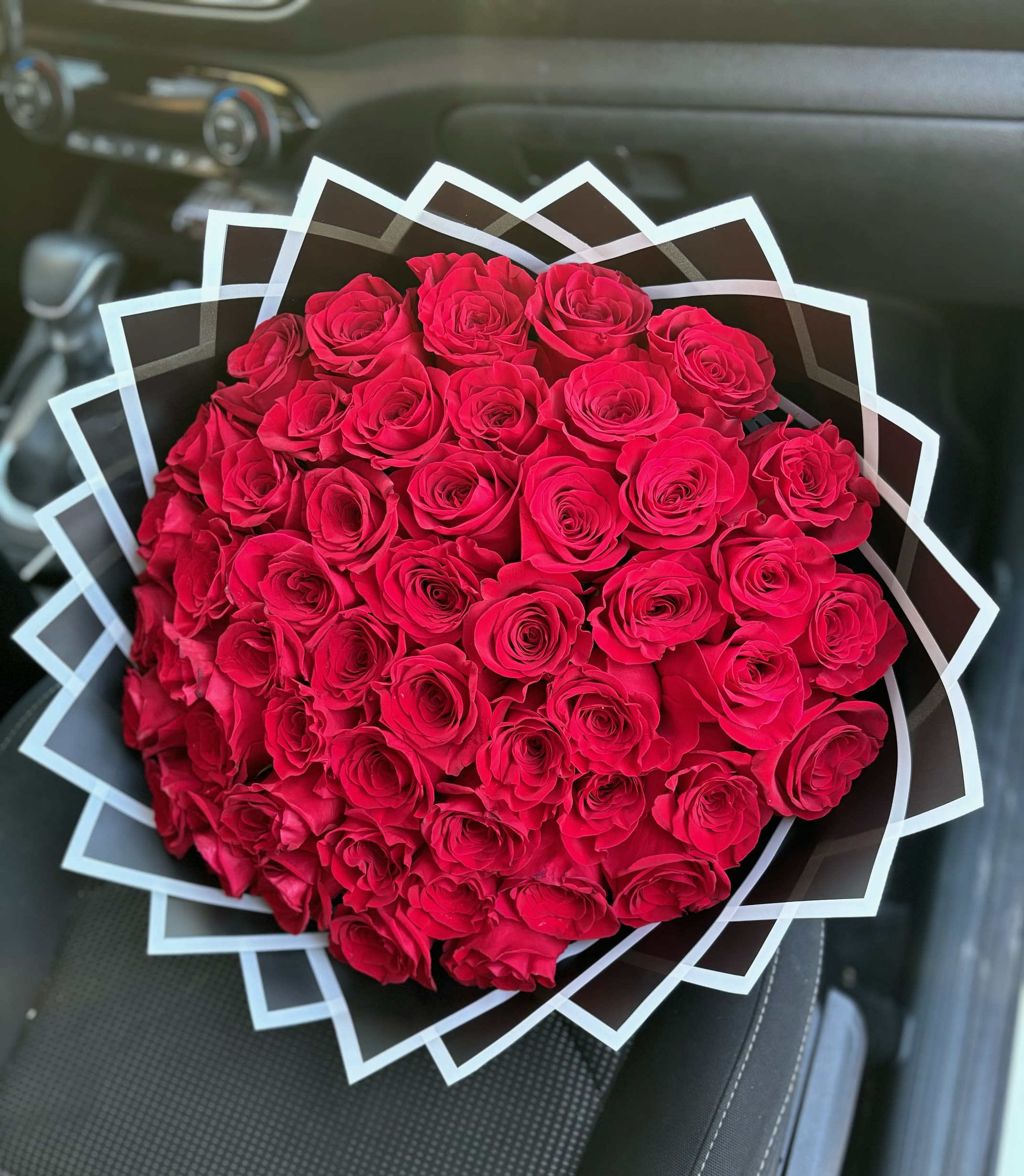 Large bouquet of red roses wrapped in geometric black and white paper