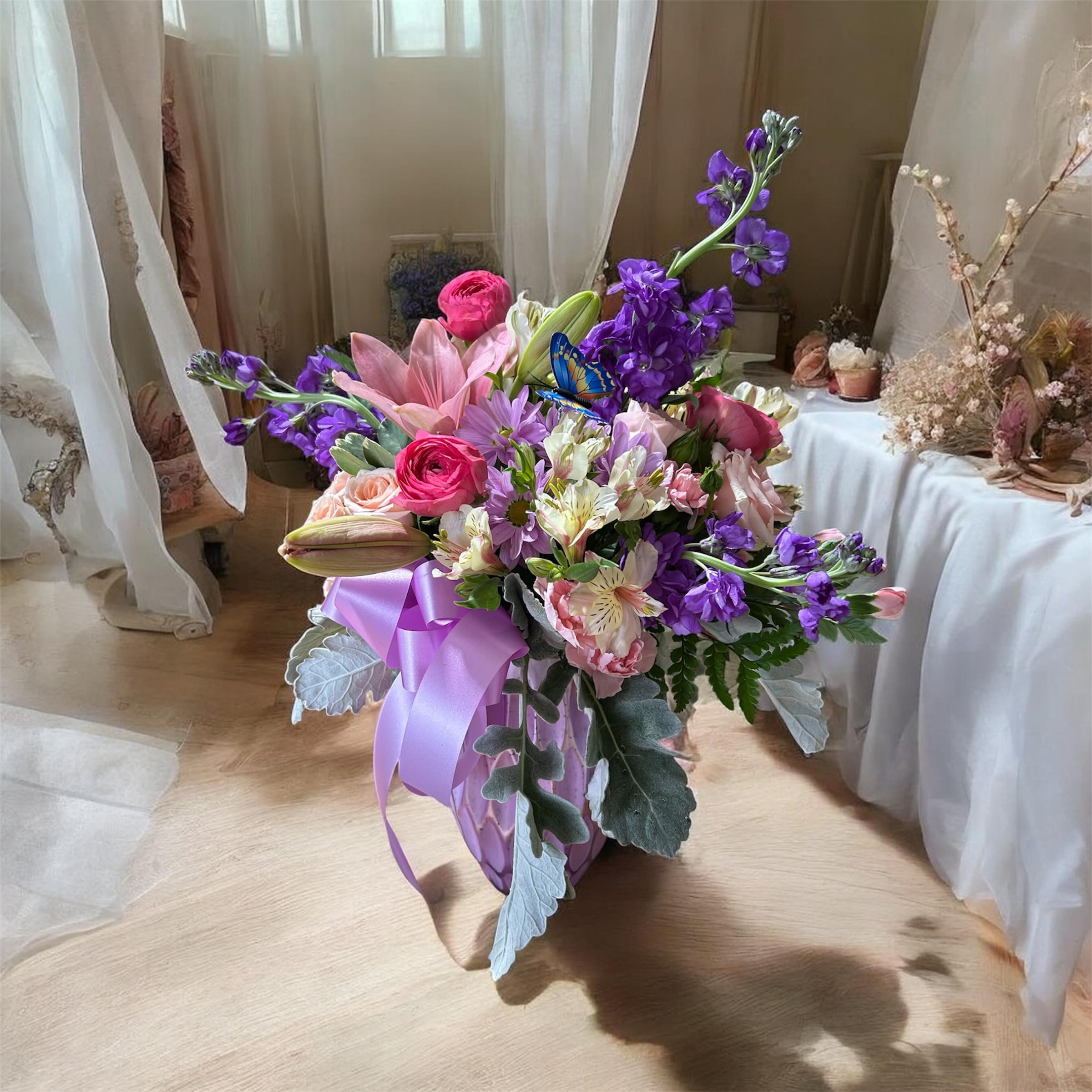     Garden Romance - A lush cascade of pinks, purples, and soft whites-this Garden Romance flower arrangement reads like a modern love letter. Perfect as an anniversary bouquet, wedding gift, or romantic surprise, it combines open lilies and garden roses with delicate ranunculus and clustered alstroemeria to create a layered, emotive centerpiece that will make the person you're thinking of feel cherished.  Touches of spiky stock and sweet daisies add texture and movement against the rounded blooms, while the lavender ribbon and decorative wrap give the hand-tied bouquet an airy, refined finish. The palette of purple, pink, white, and lavender lends a soft, elegant mood that works beautifully for bridal events, milestone celebrations, or simply saying "I love you" in a meaningful way.  Designed to look full and freshly gathered, Garden Romance arrives ready to display; trim stems and place in fresh water to extend vase life. Its romantic color story and varied flower forms make it the kind of bouquet that reads as both thoughtfully arranged and effortlessly natural-ideal for the person who deserves to feel truly seen.