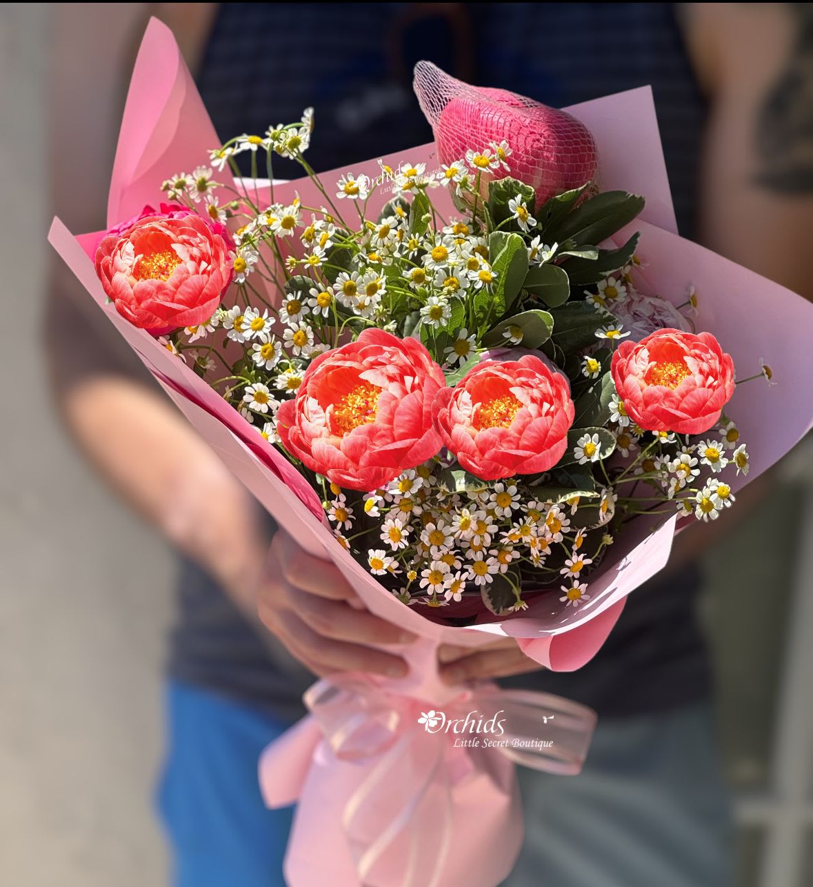 Pink bouquet with coral flowers and small white daisies wrapped in pink paper