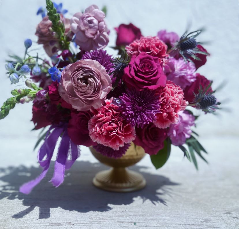 Pink and purple flower arrangement in a gold pedestal vase