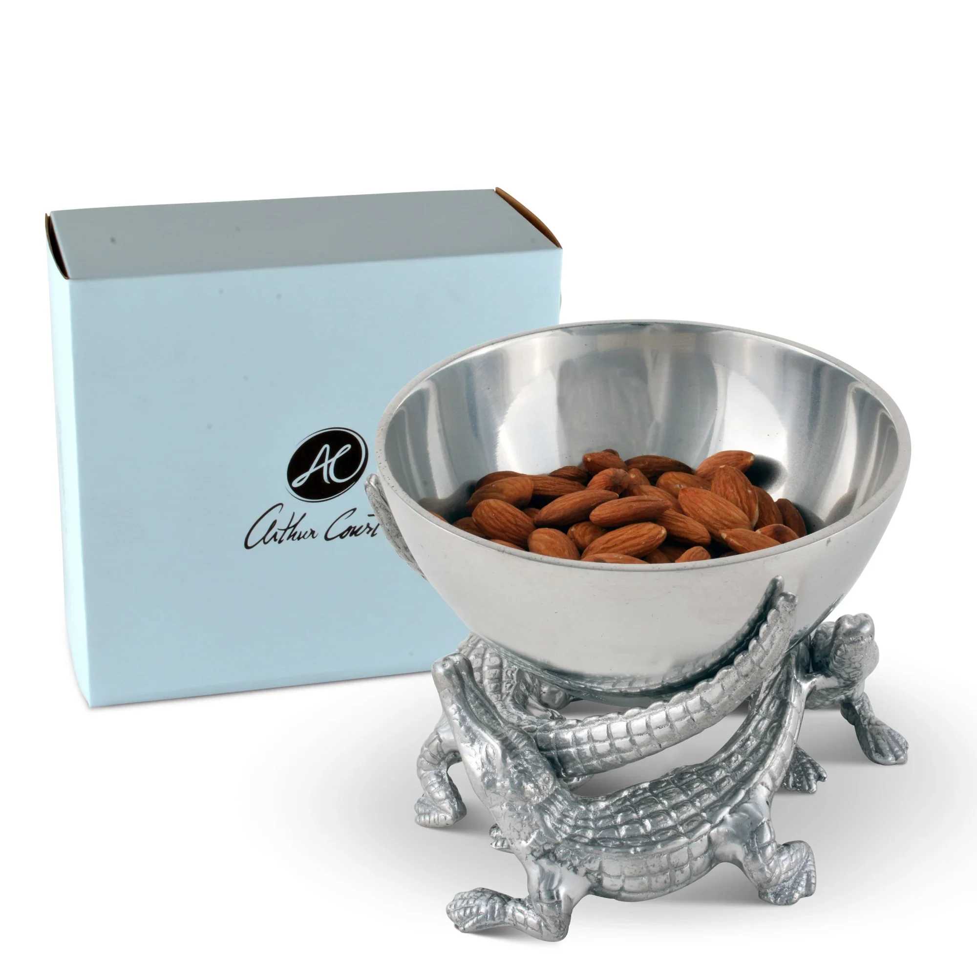 Silver bowl on a crocodile stand filled with almonds, with a light blue box behind it.